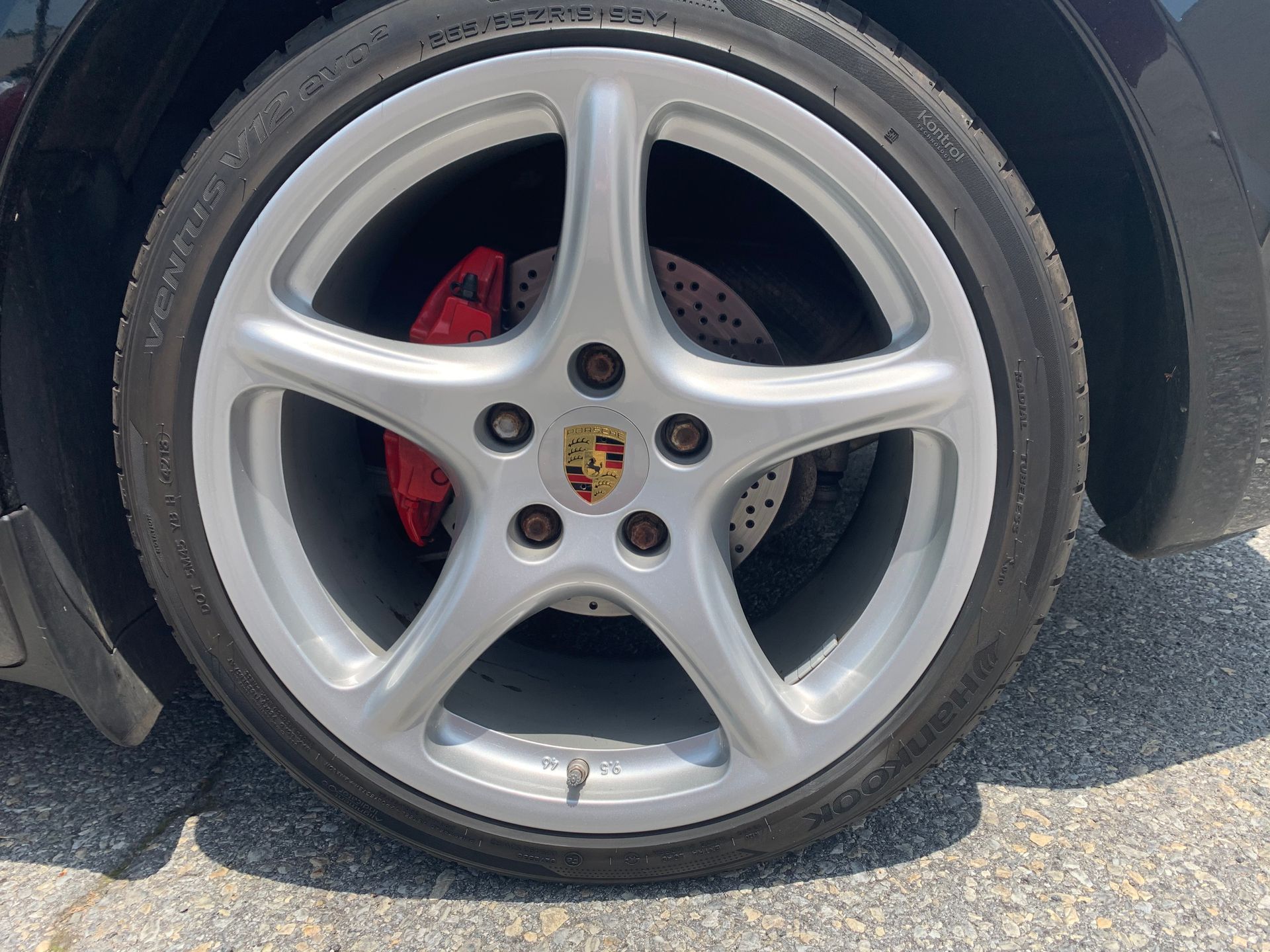 Close-up of a silver Porsche wheel with red brake caliper and drilled brake disc