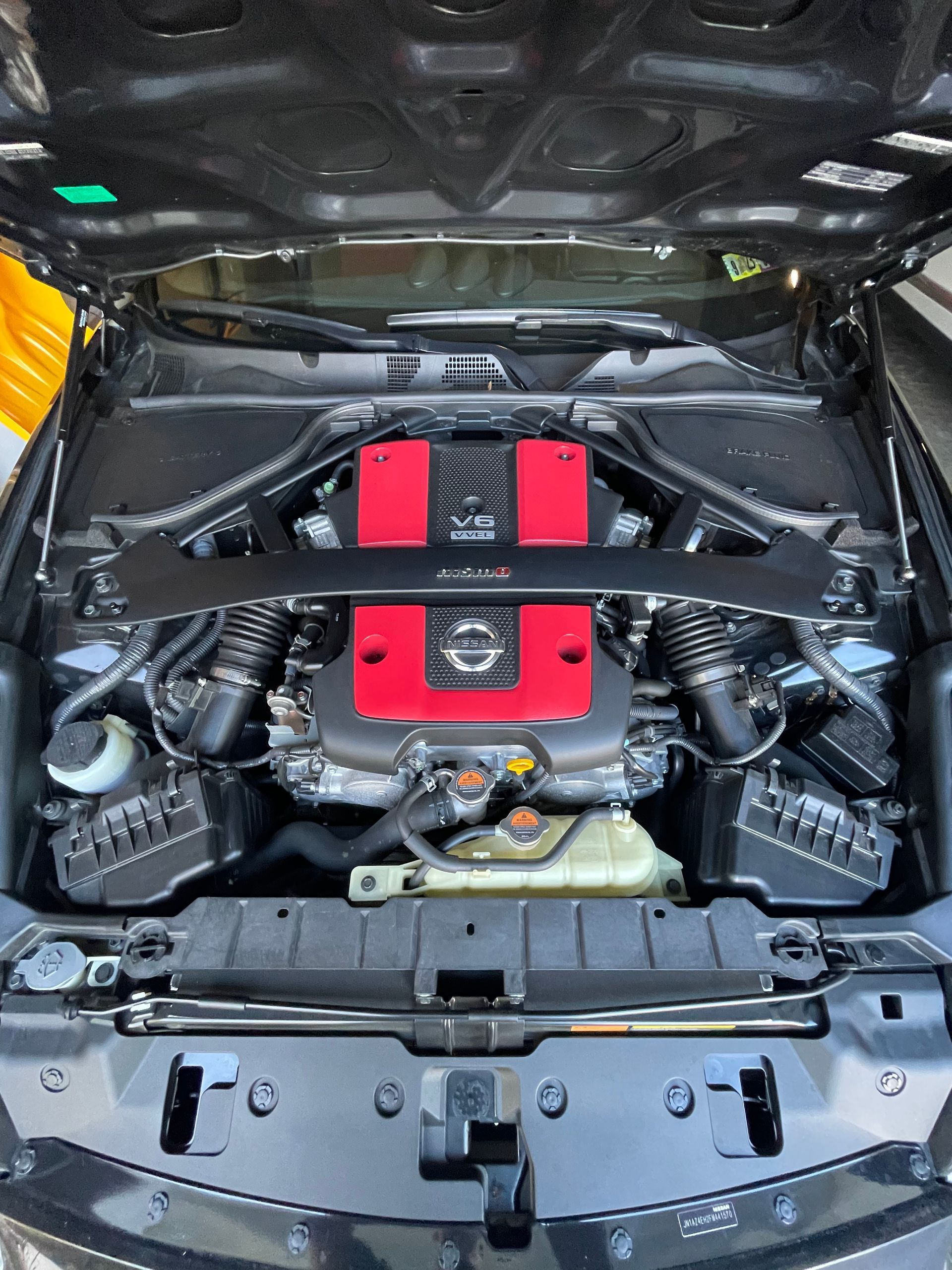 Car engine bay with red and black components under an open hood
