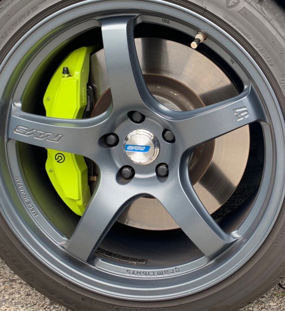 Close-up of a gray alloy wheel with a bright yellow brake caliper and black tire