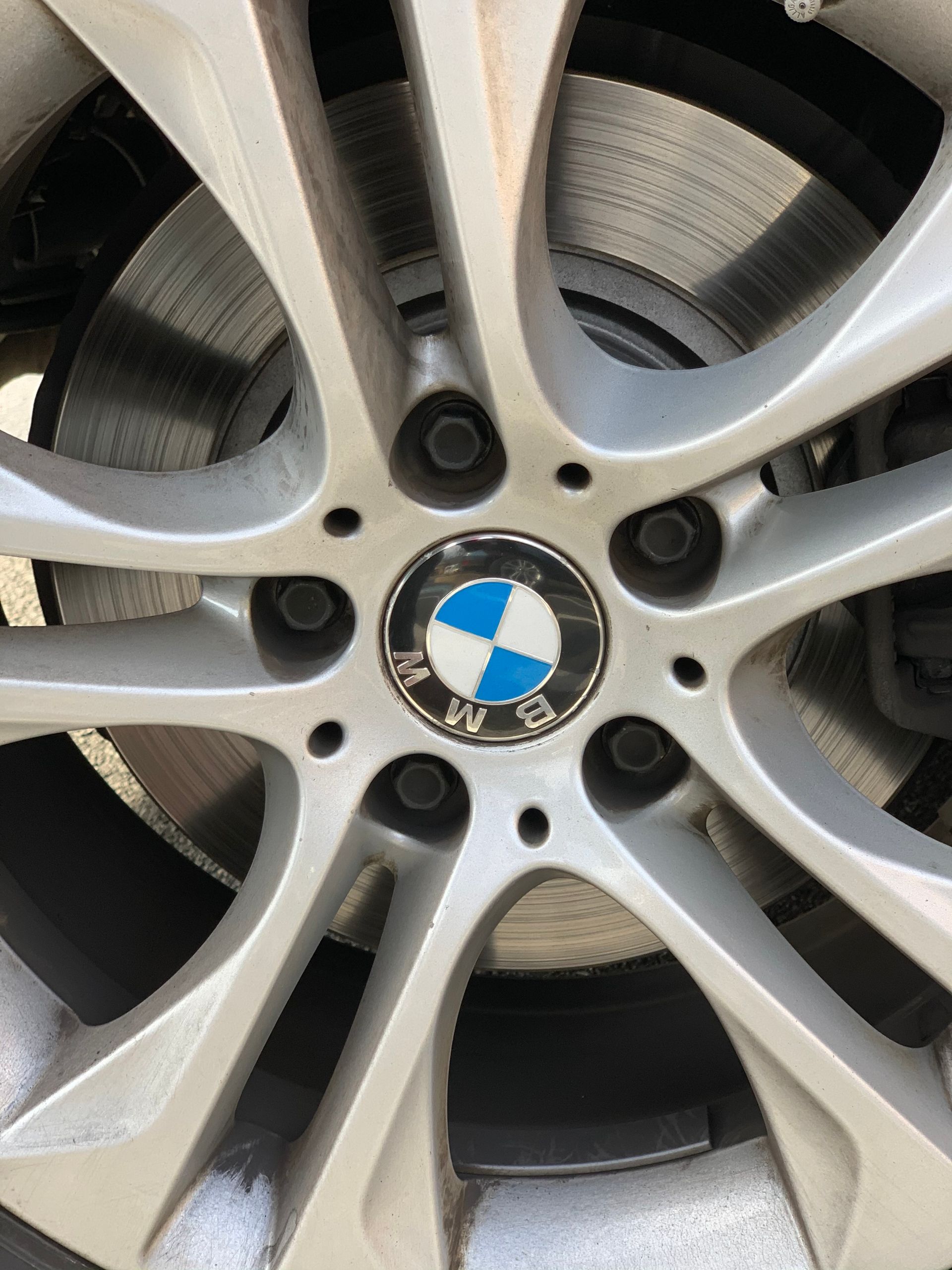 Close-up of a BMW alloy wheel with silver spokes and the blue-and-white logo at the center.
