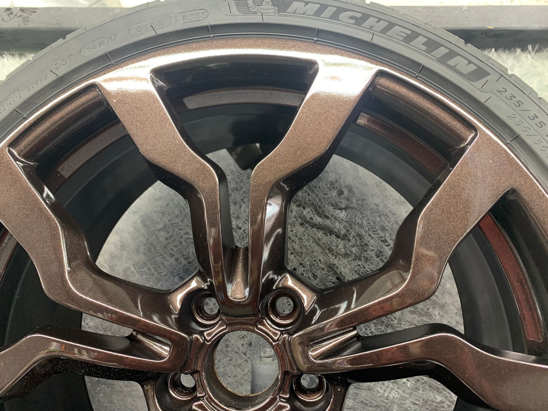 Close-up of a bronze alloy car wheel rim with tire tread visible
