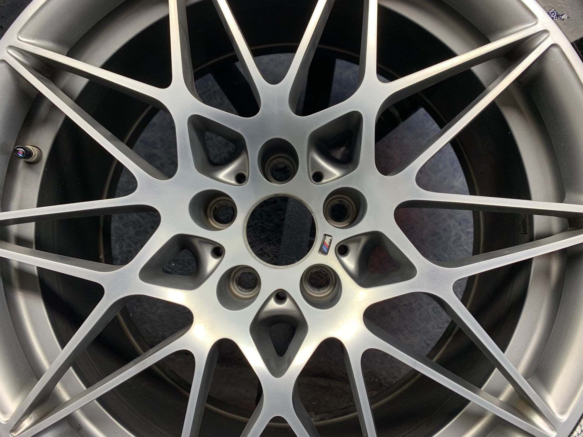 Close-up of a silver alloy car wheel rim with multiple spokes and lug holes