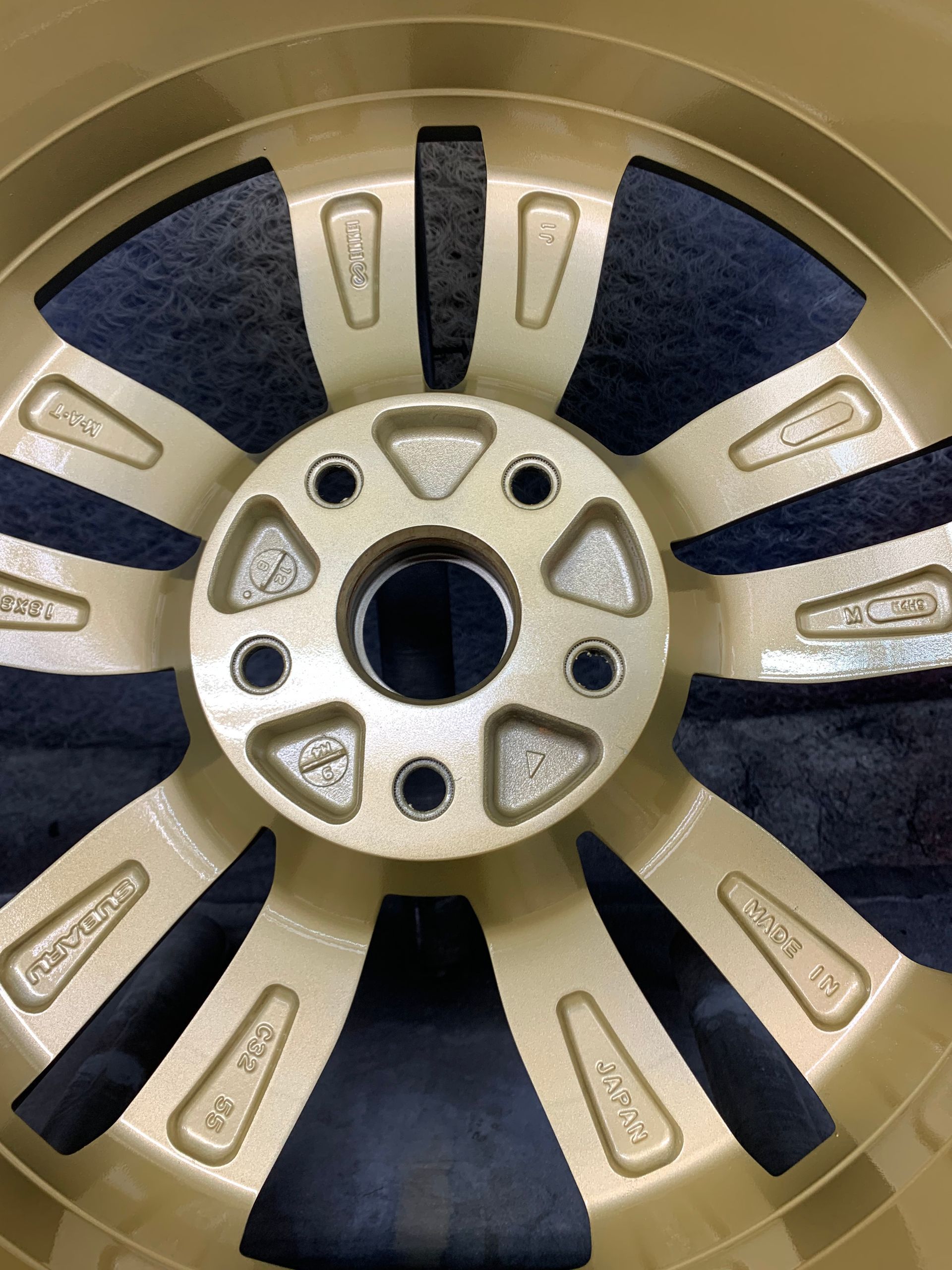 Close-up of a gold and black car wheel rim with a five-spoke star pattern