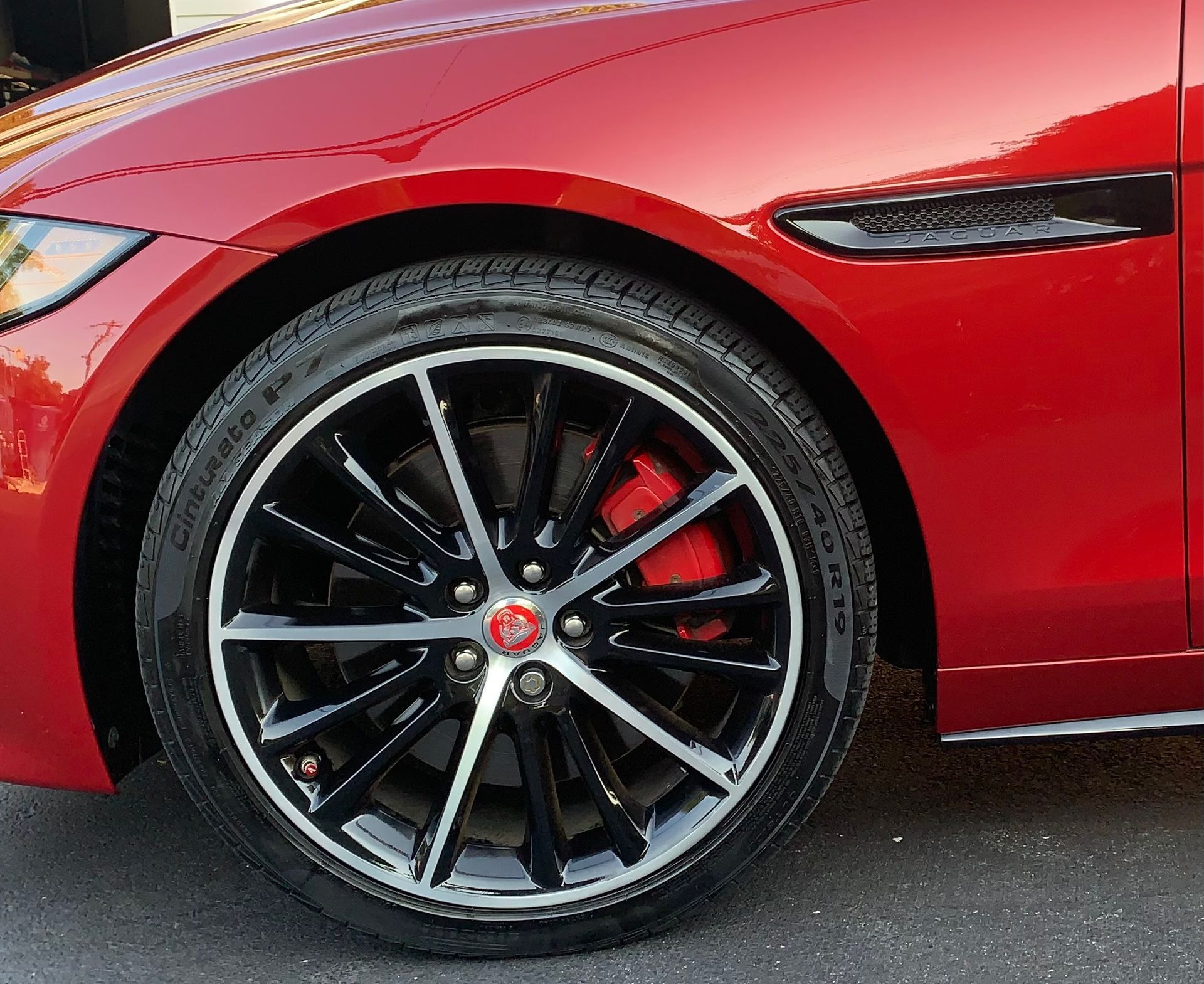 Close-up of a red sports car’s front wheel with black alloy rim and red brake caliper.