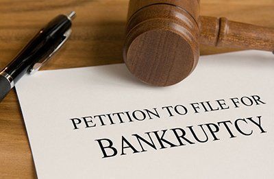 Petition to file for bankruptcy, with a gavel and pen on a wooden surface.