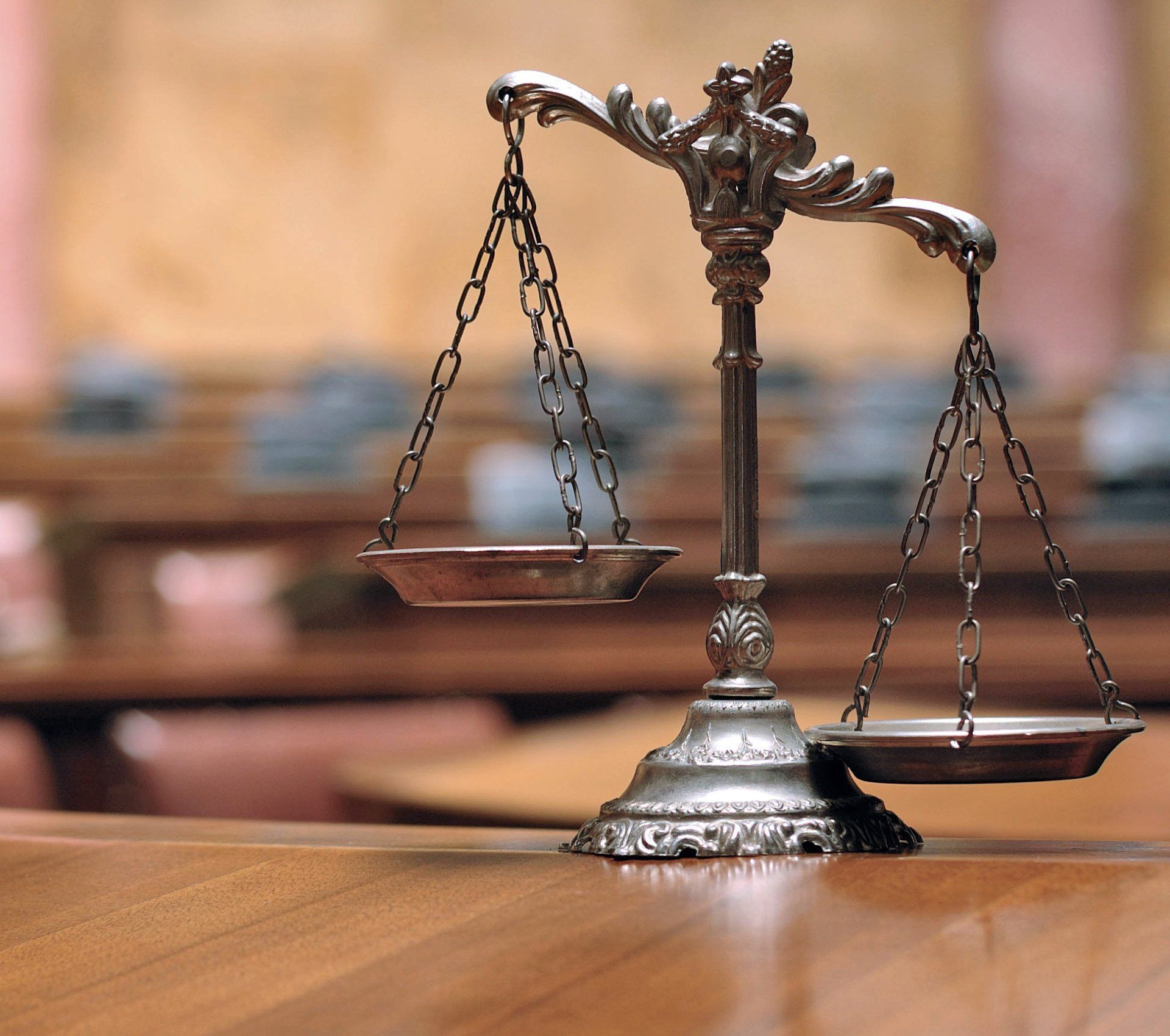 Scales of justice on a wooden surface in a courtroom.