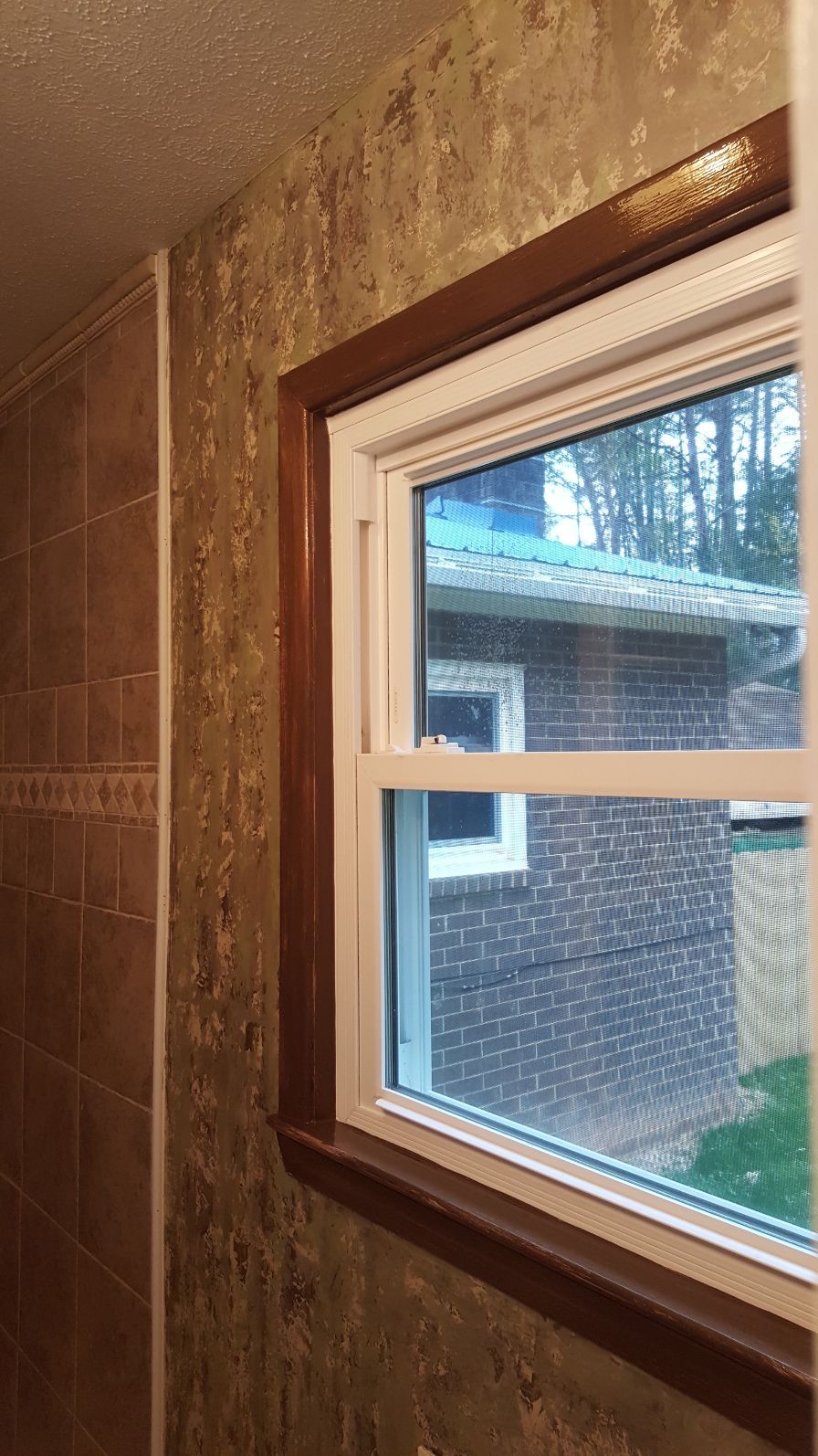 A bathroom with a window and a brick wall.