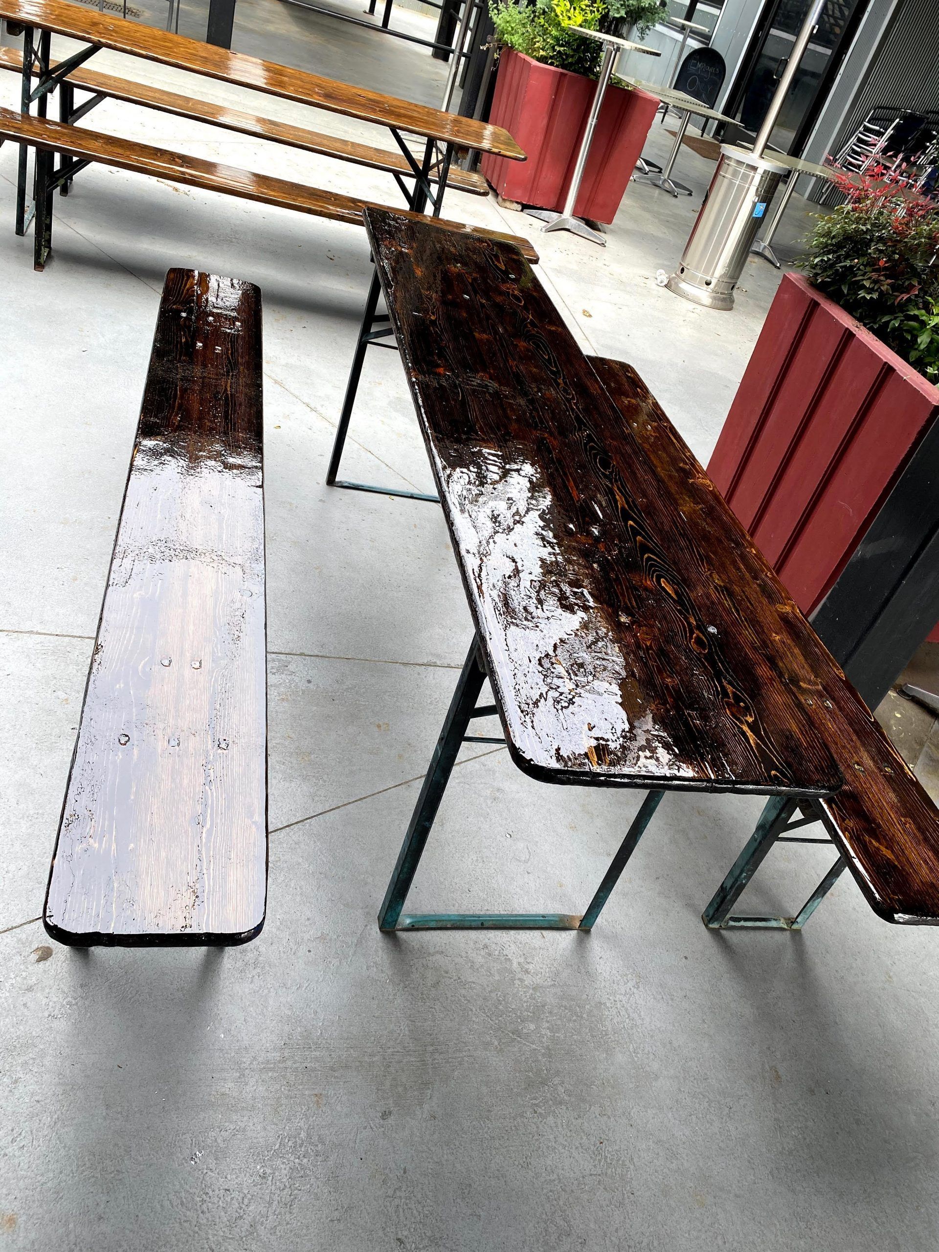 A table and bench are covered in dirt on a patio.