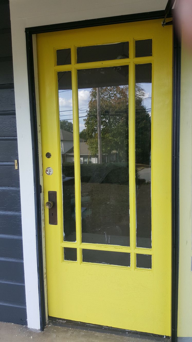 A yellow door with a black frame is on a building.