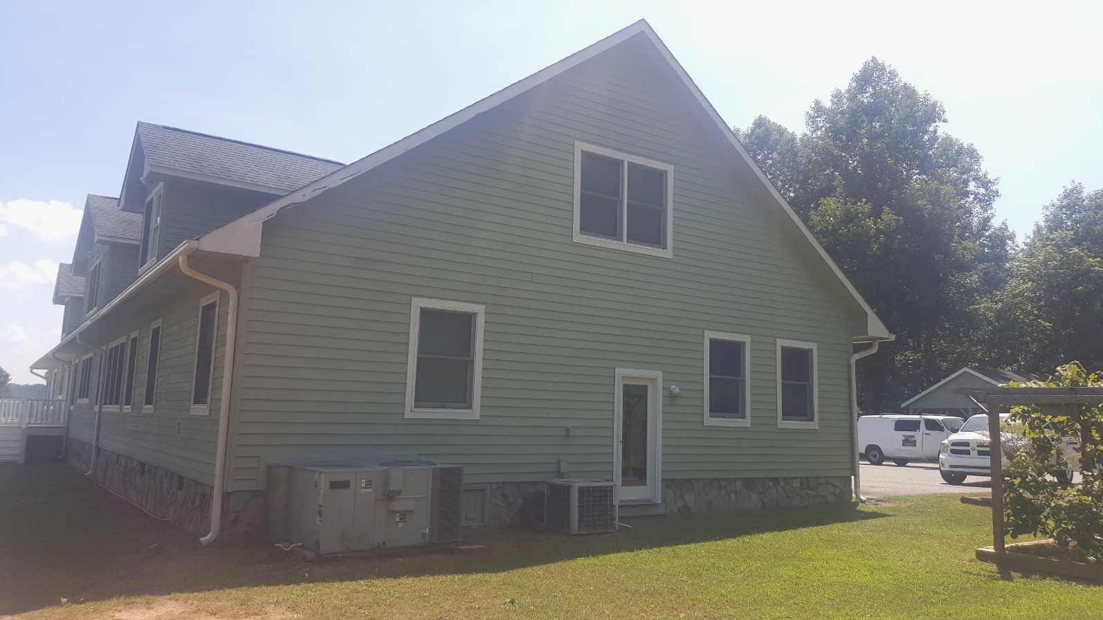 A large green house with a black roof is sitting on top of a lush green field.