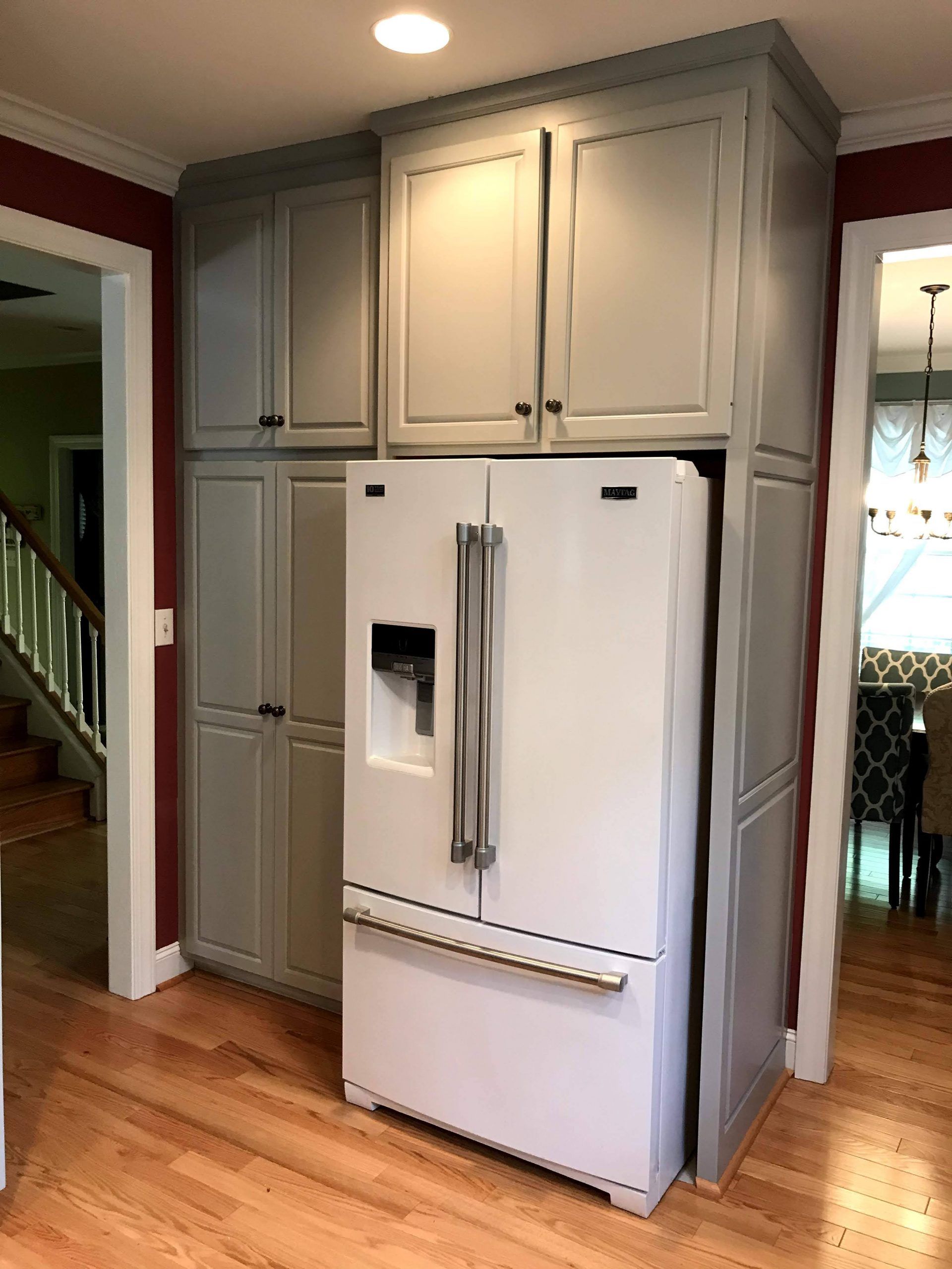 A white refrigerator is sitting in a kitchen surrounded by cabinets.
