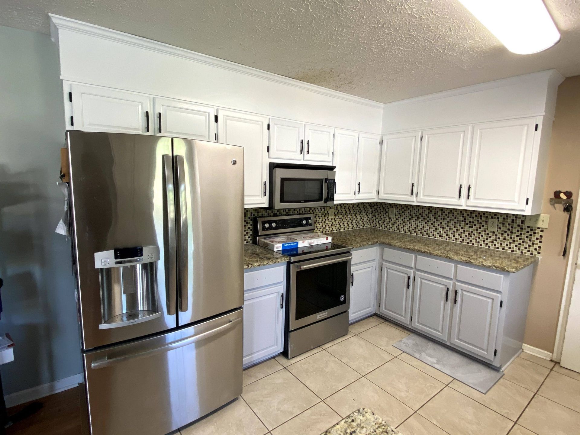 A kitchen with stainless steel appliances and white cabinets.