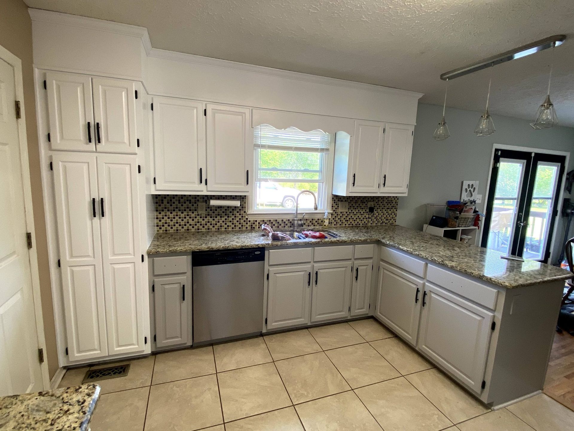 A kitchen with white cabinets , granite counter tops , and stainless steel appliances.