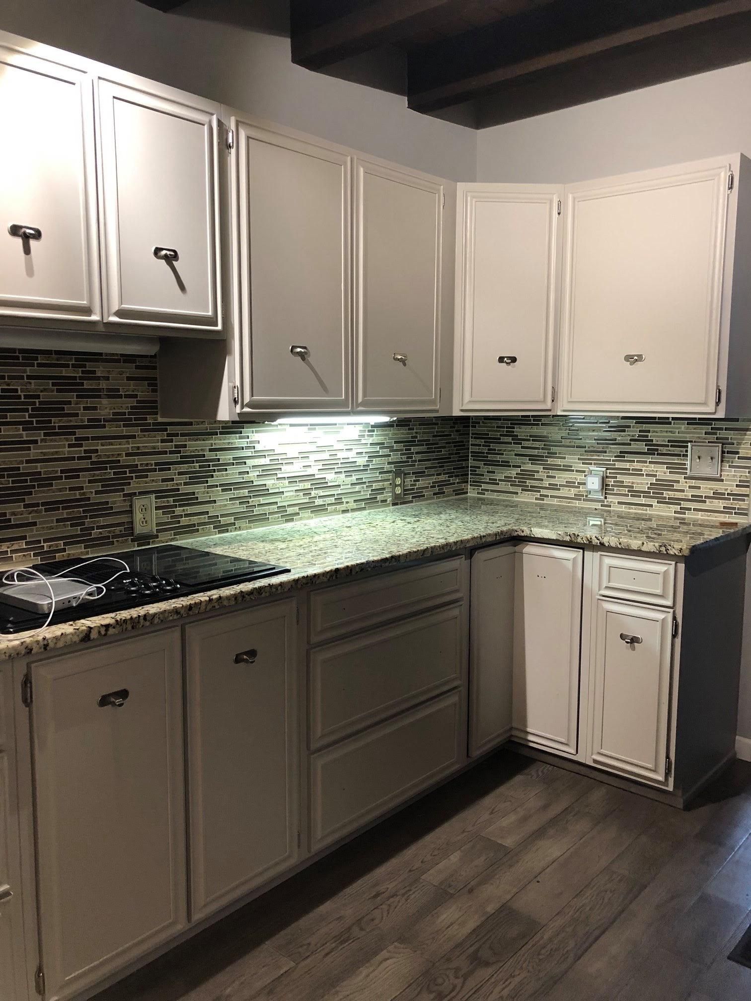 A kitchen with white cabinets and granite counter tops.