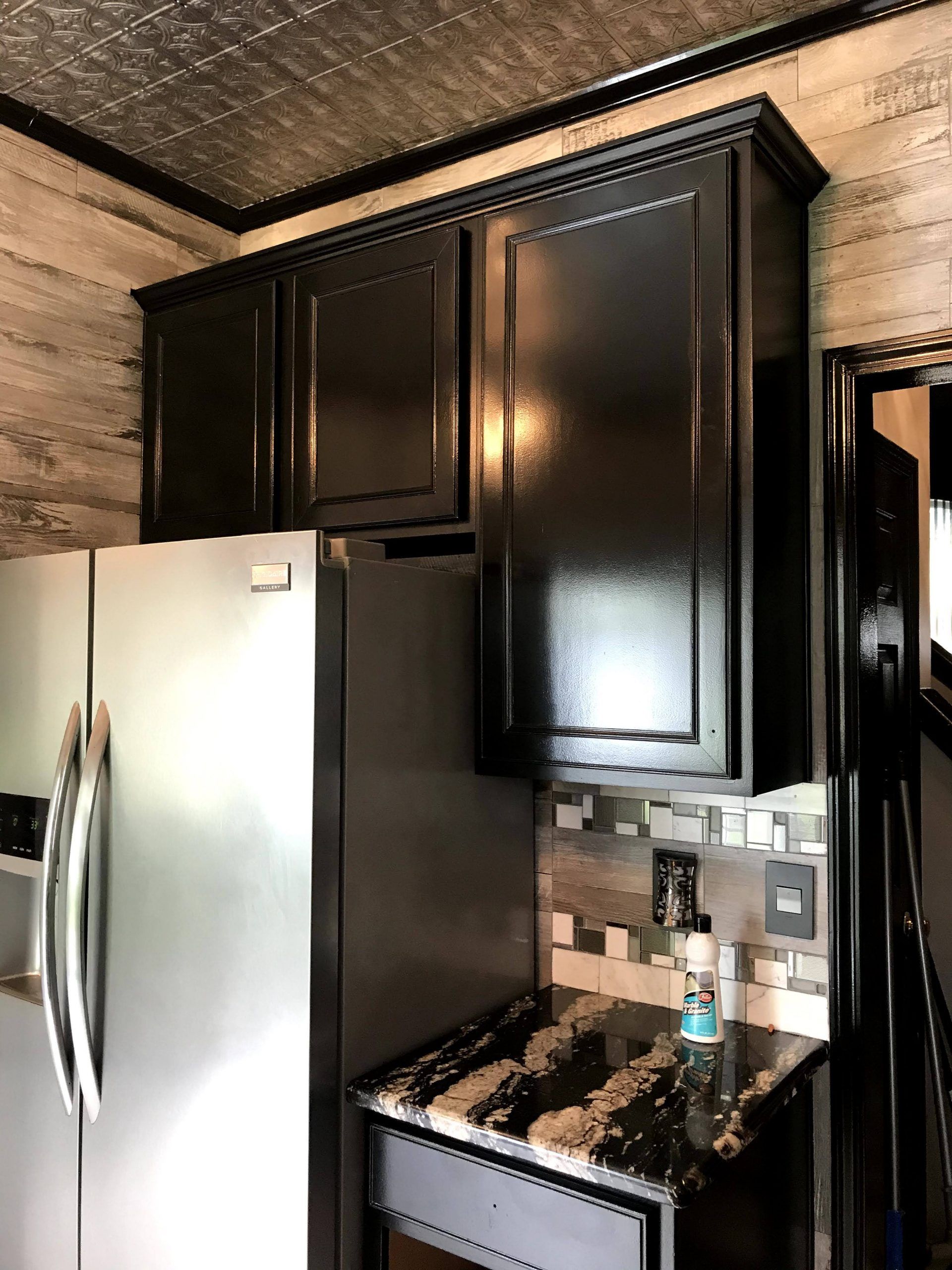 A kitchen with black cabinets , a refrigerator , and a stove.