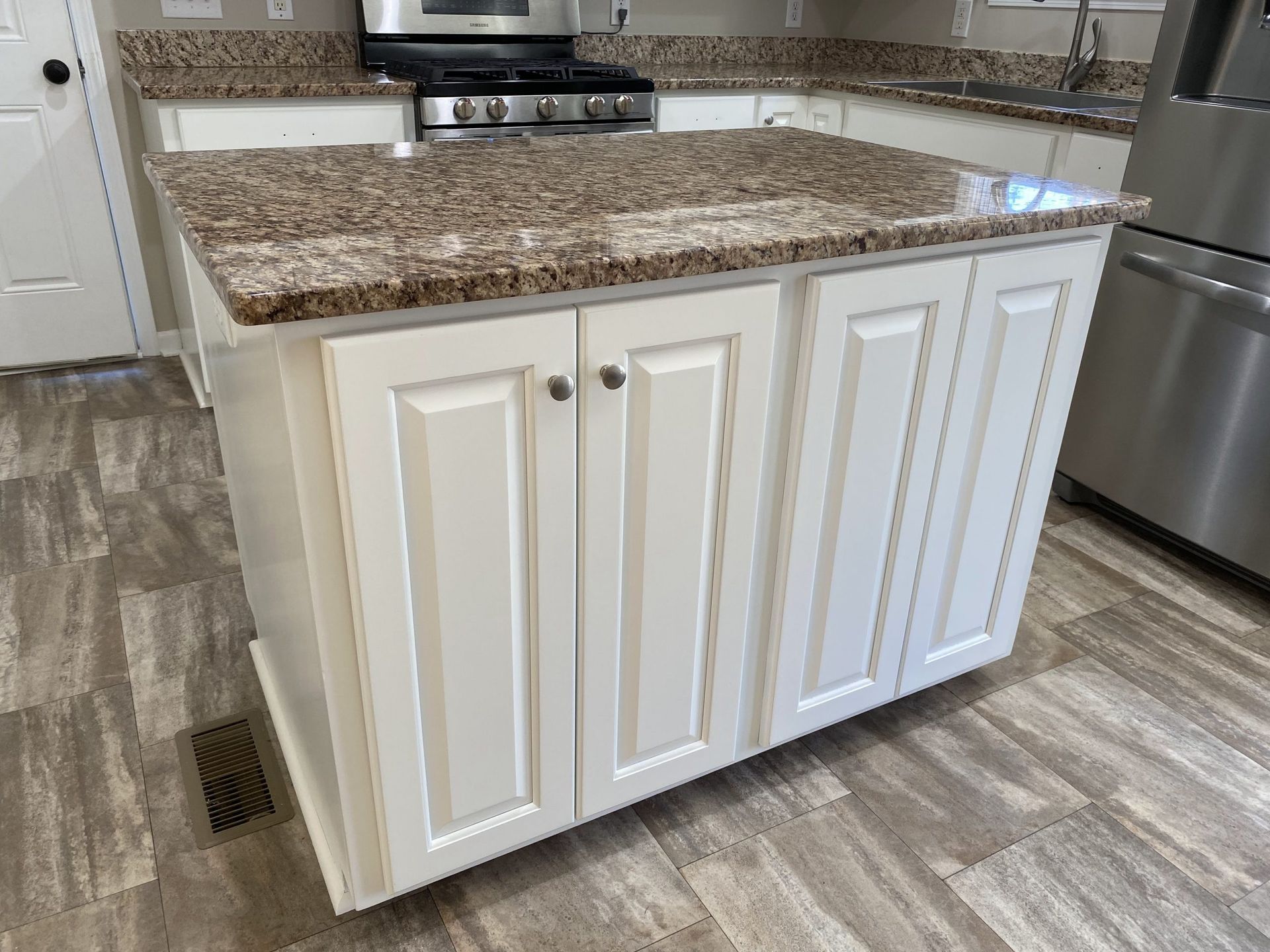 A kitchen with white cabinets and granite counter tops.
