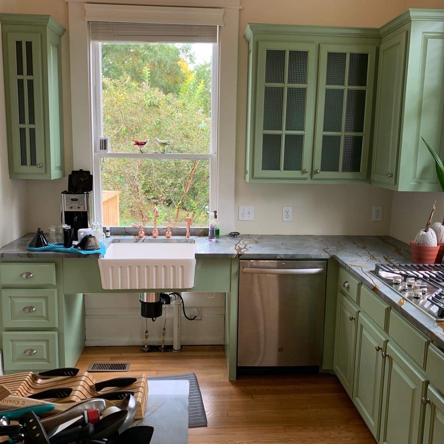 A kitchen with green cabinets and a white sink