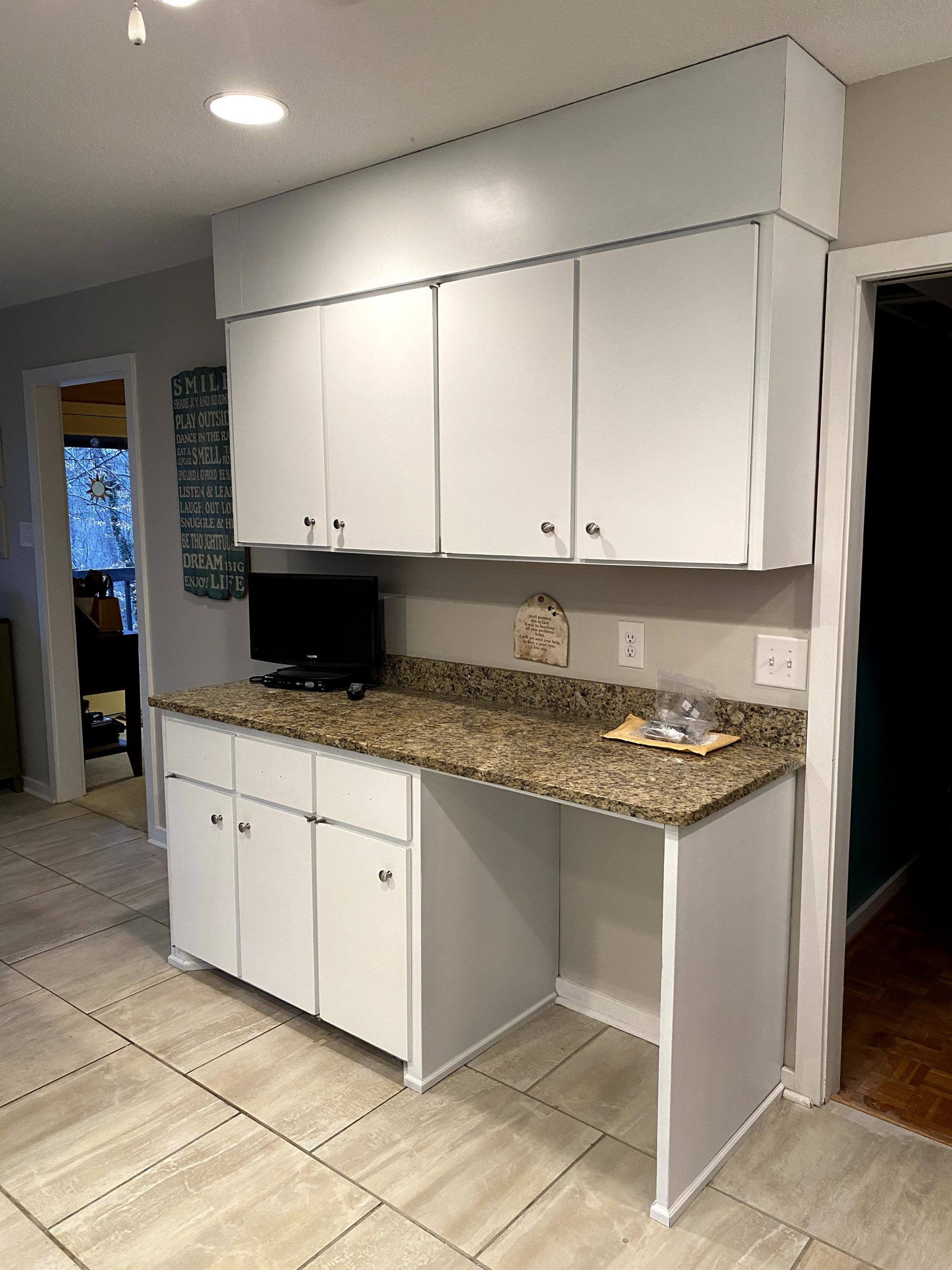 A kitchen with white cabinets and granite counter tops.
