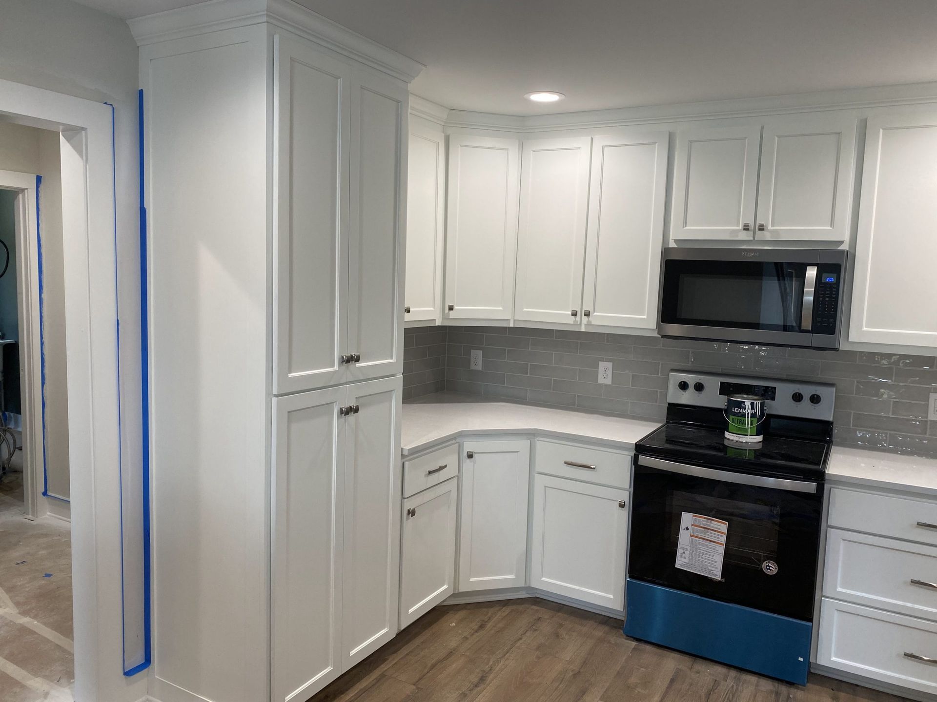A kitchen with white cabinets , a stove , and a microwave.
