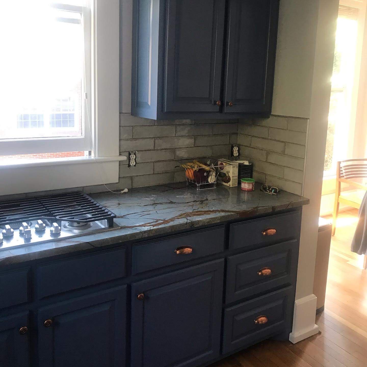 A kitchen with blue cabinets and a stove top oven.