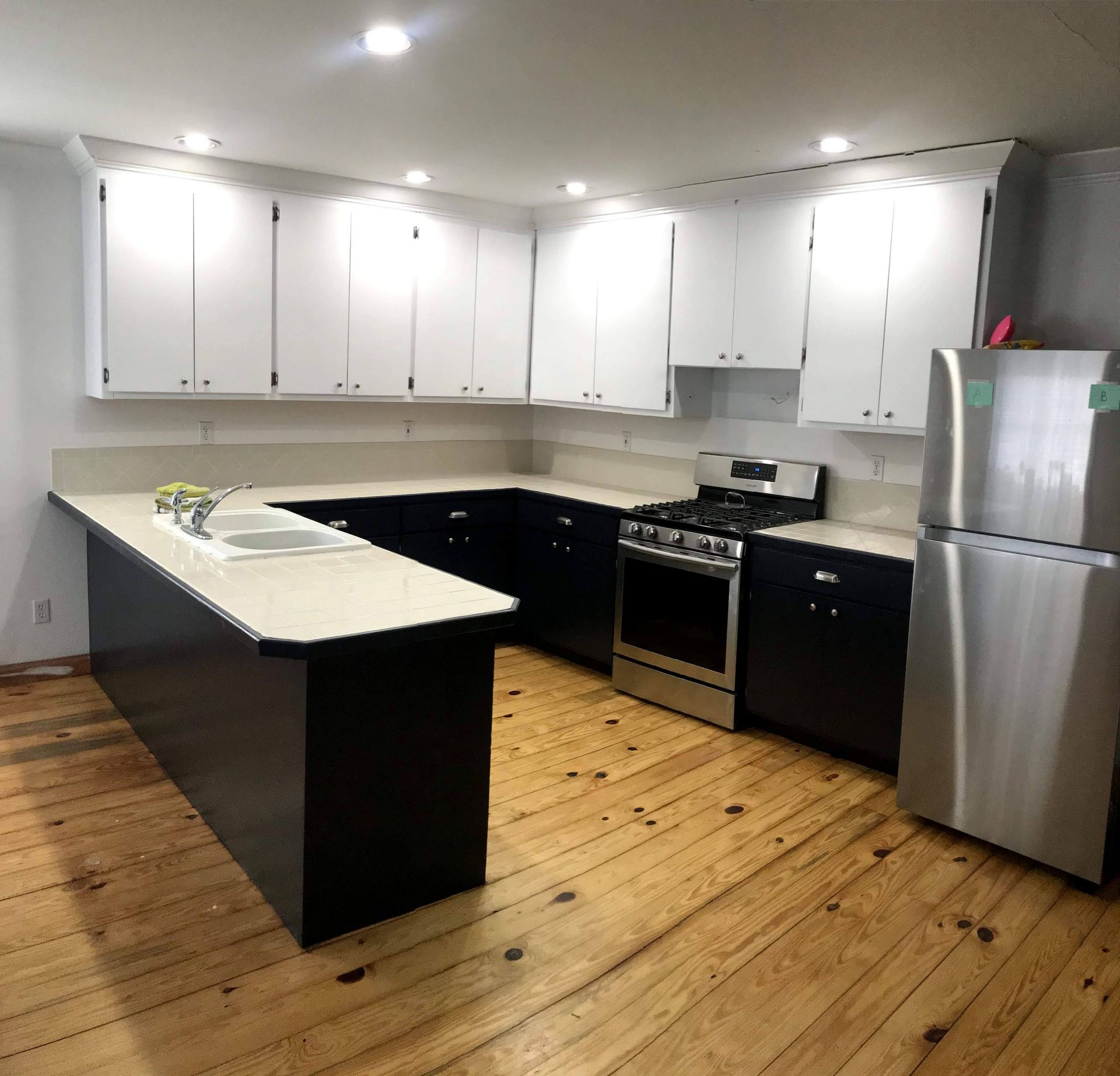 A kitchen with white cabinets and a stainless steel refrigerator