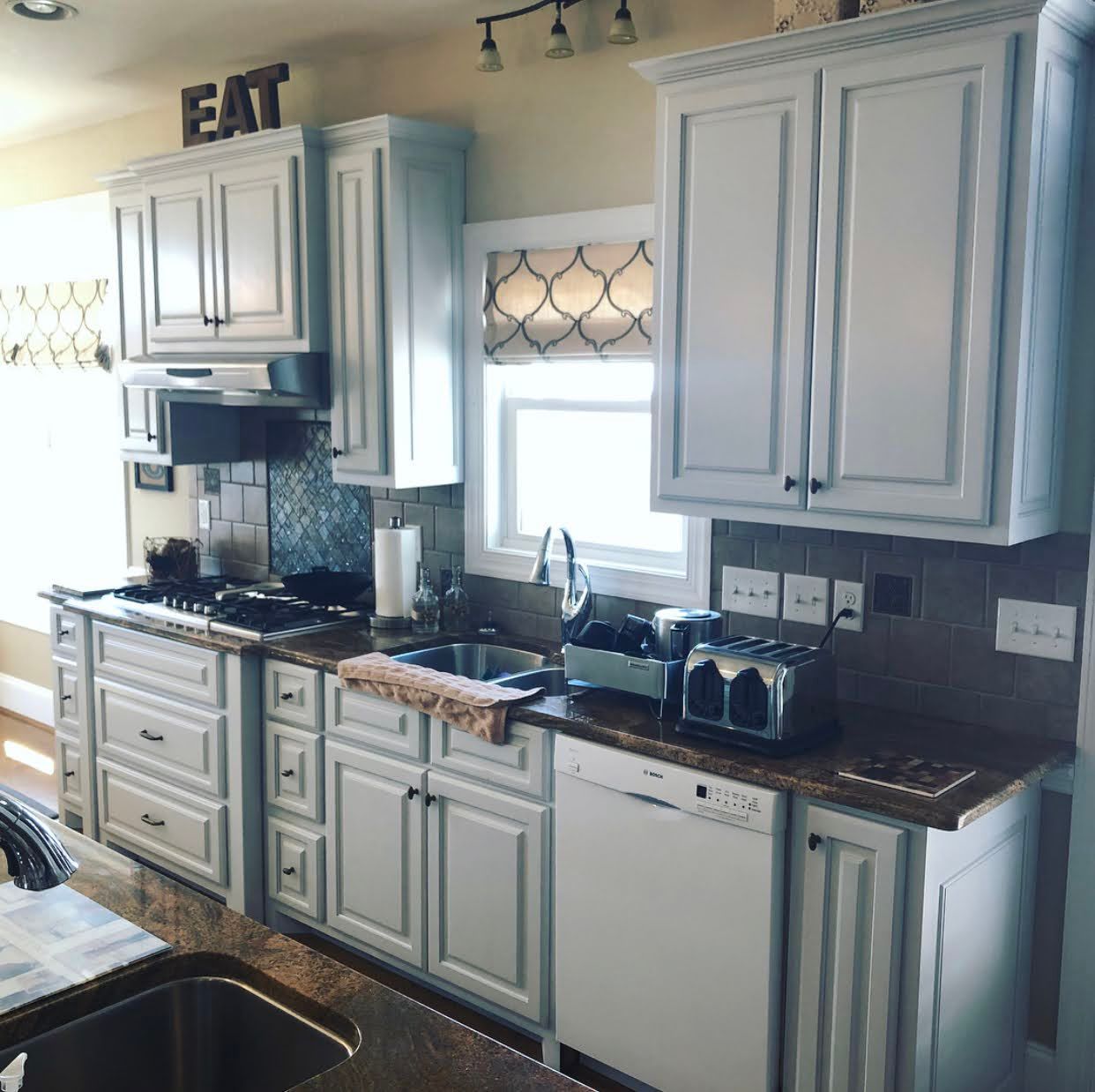 A kitchen with white cabinets and a sign that says eat