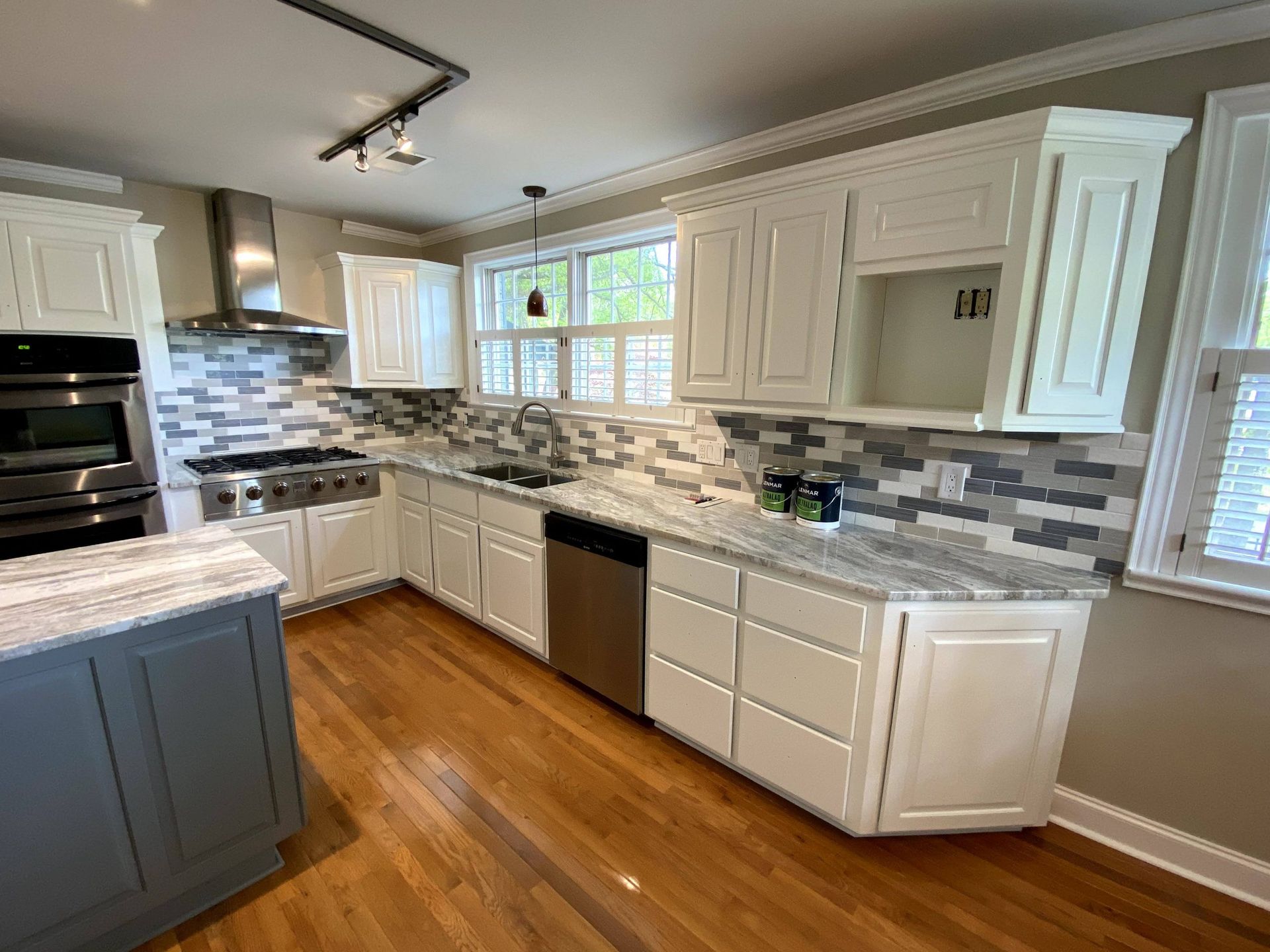 A kitchen with white cabinets , granite counter tops , stainless steel appliances , and hardwood floors.