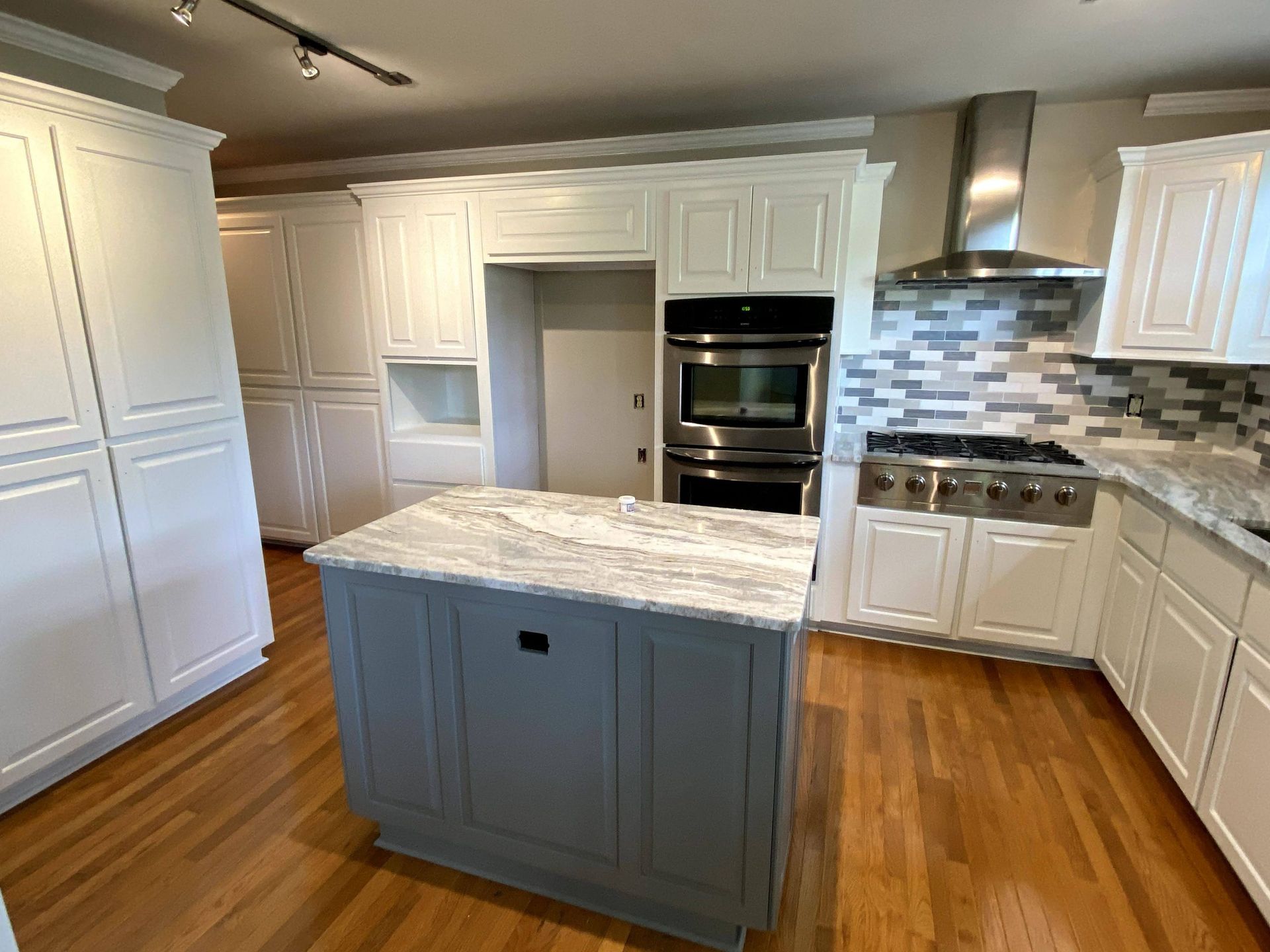 A kitchen with white cabinets and a large island in the middle.