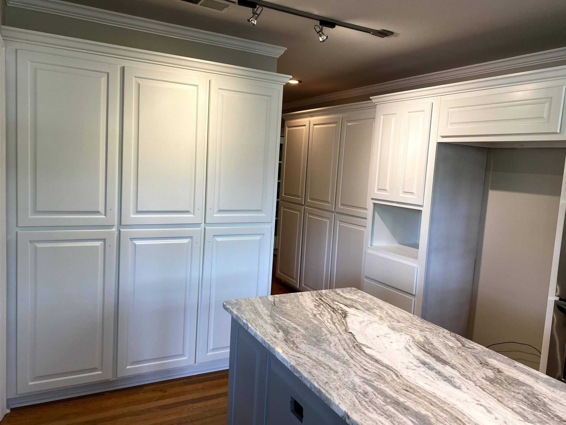 A kitchen with white cabinets and a granite counter top.