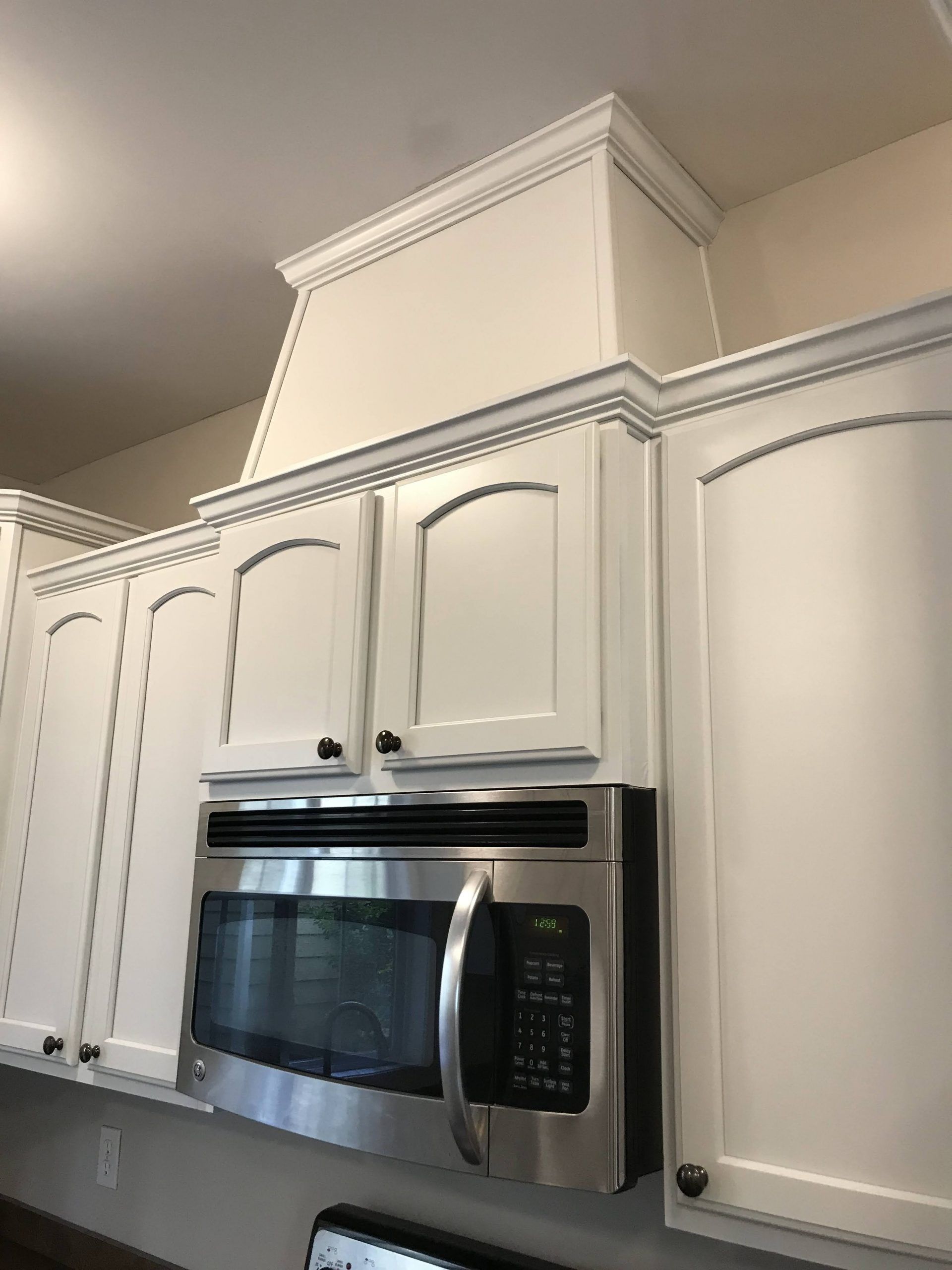 A kitchen with white cabinets and a stainless steel microwave oven