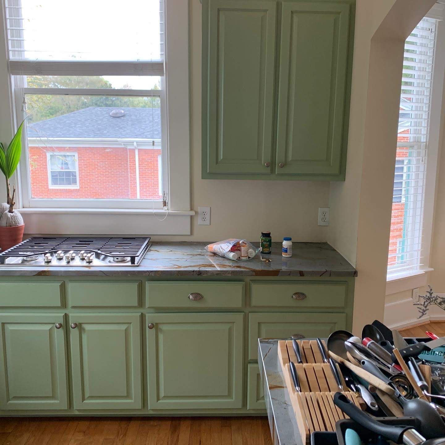 A kitchen with green cabinets and a stove top oven