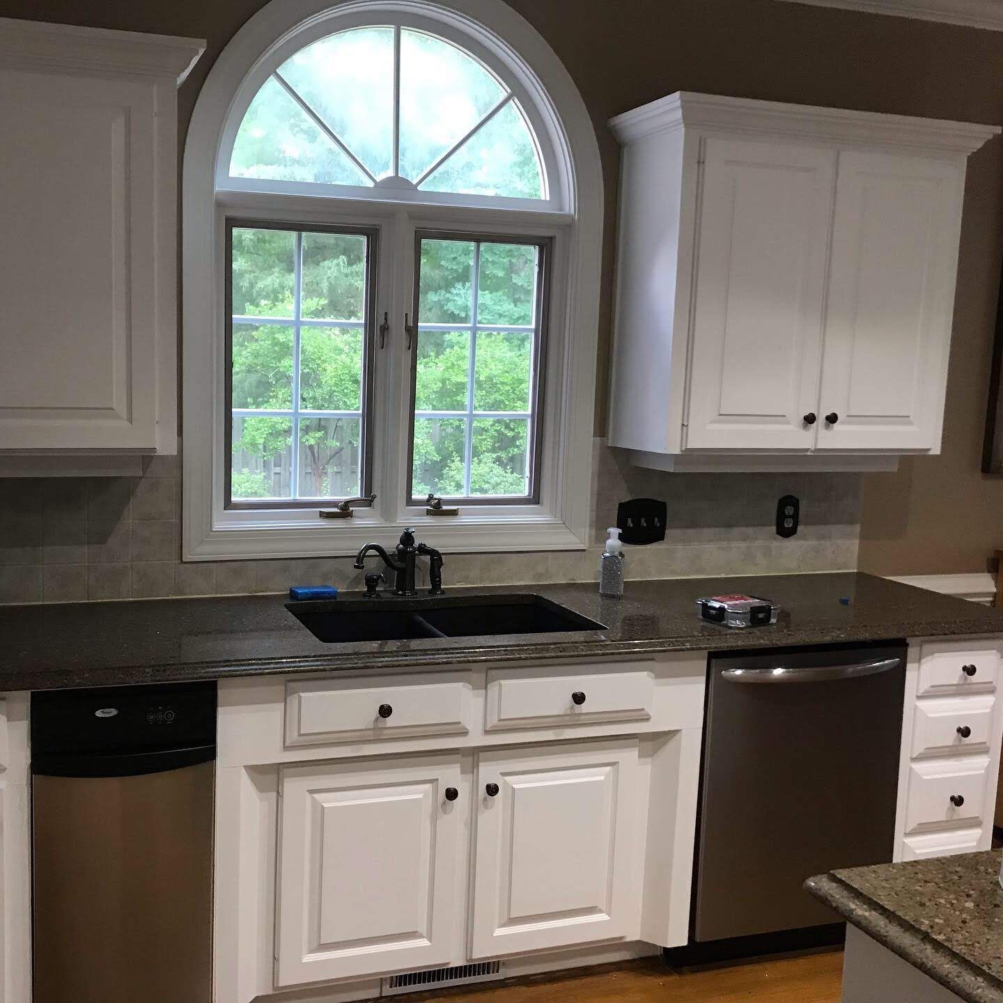 A kitchen with white cabinets and a stainless steel dishwasher