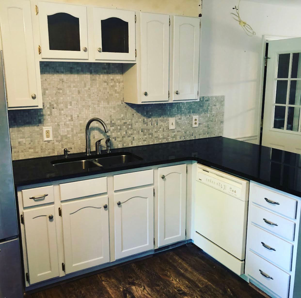 A kitchen with white cabinets and black counter tops