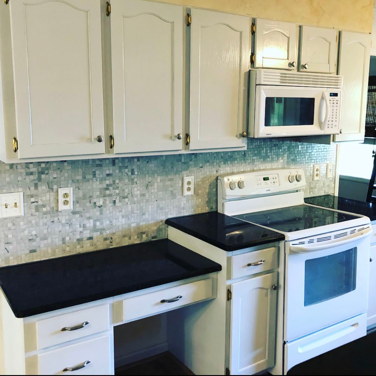 A kitchen with white cabinets and black counter tops