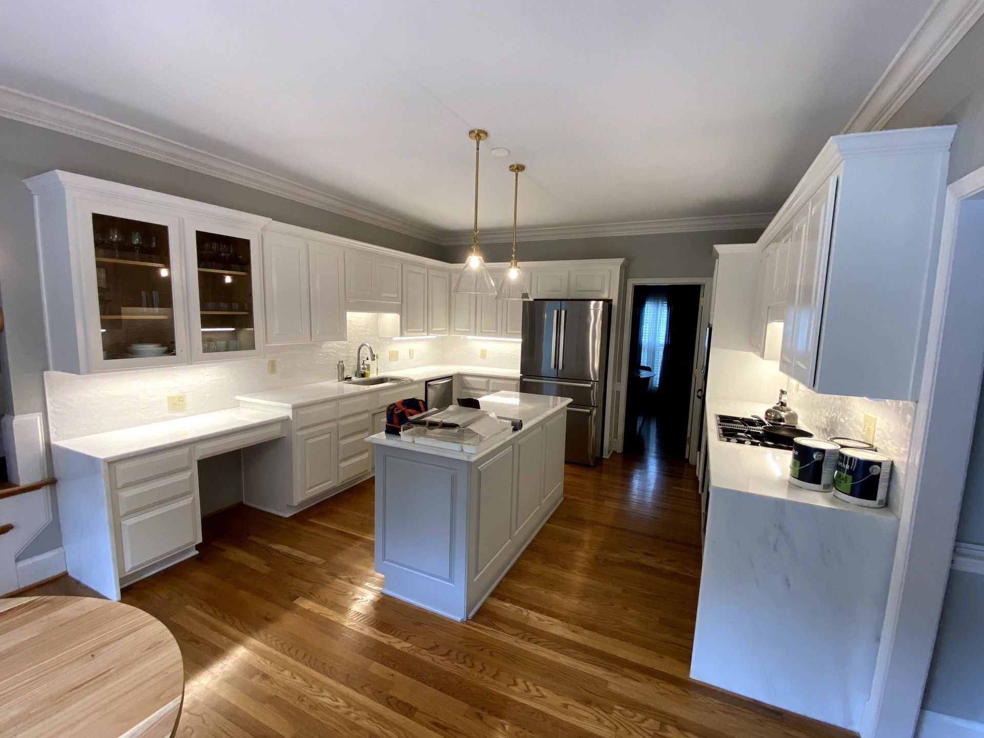 A kitchen with white cabinets and hardwood floors and a large island in the middle.