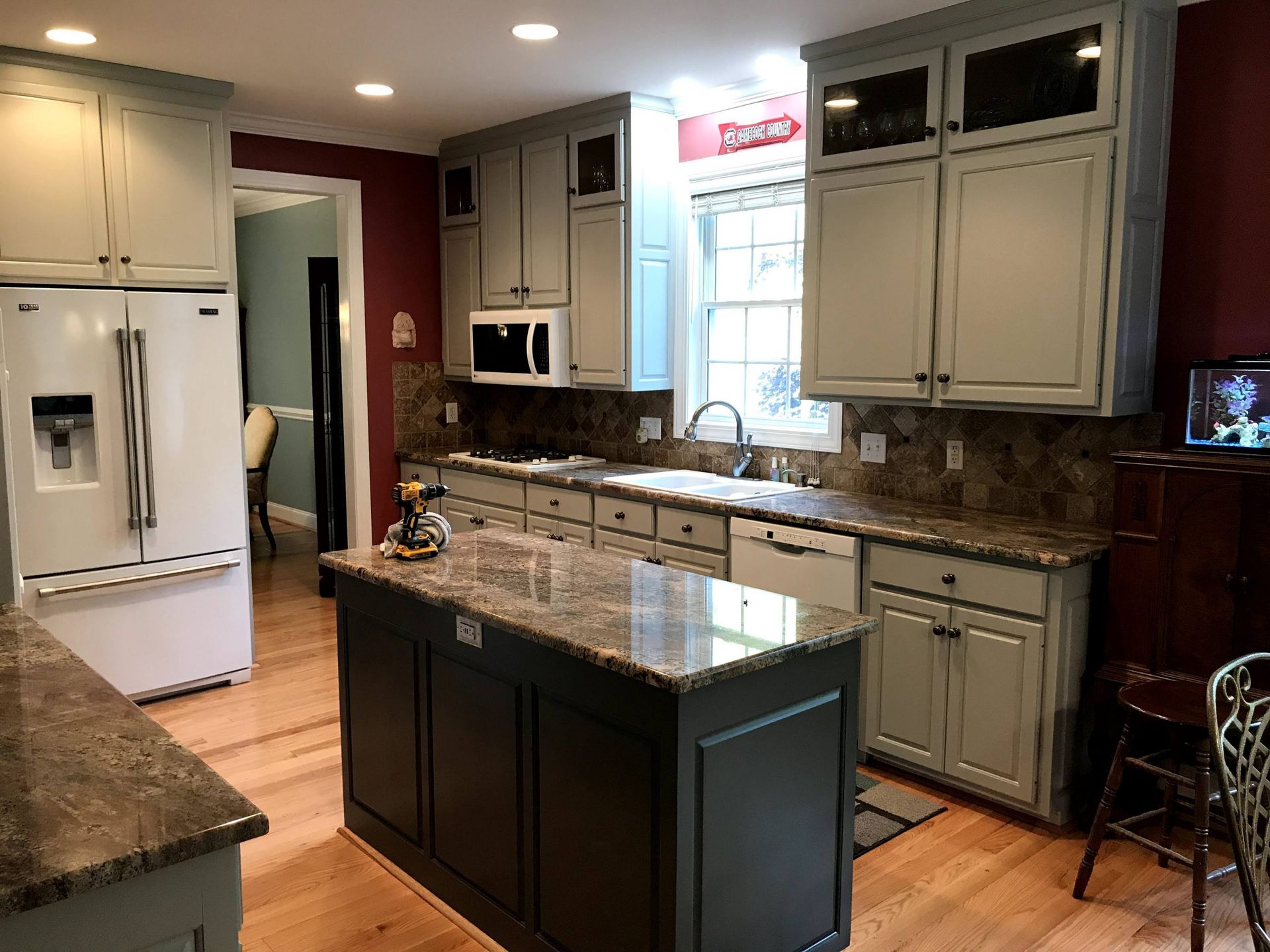 A kitchen with white cabinets , granite counter tops , and a large island.