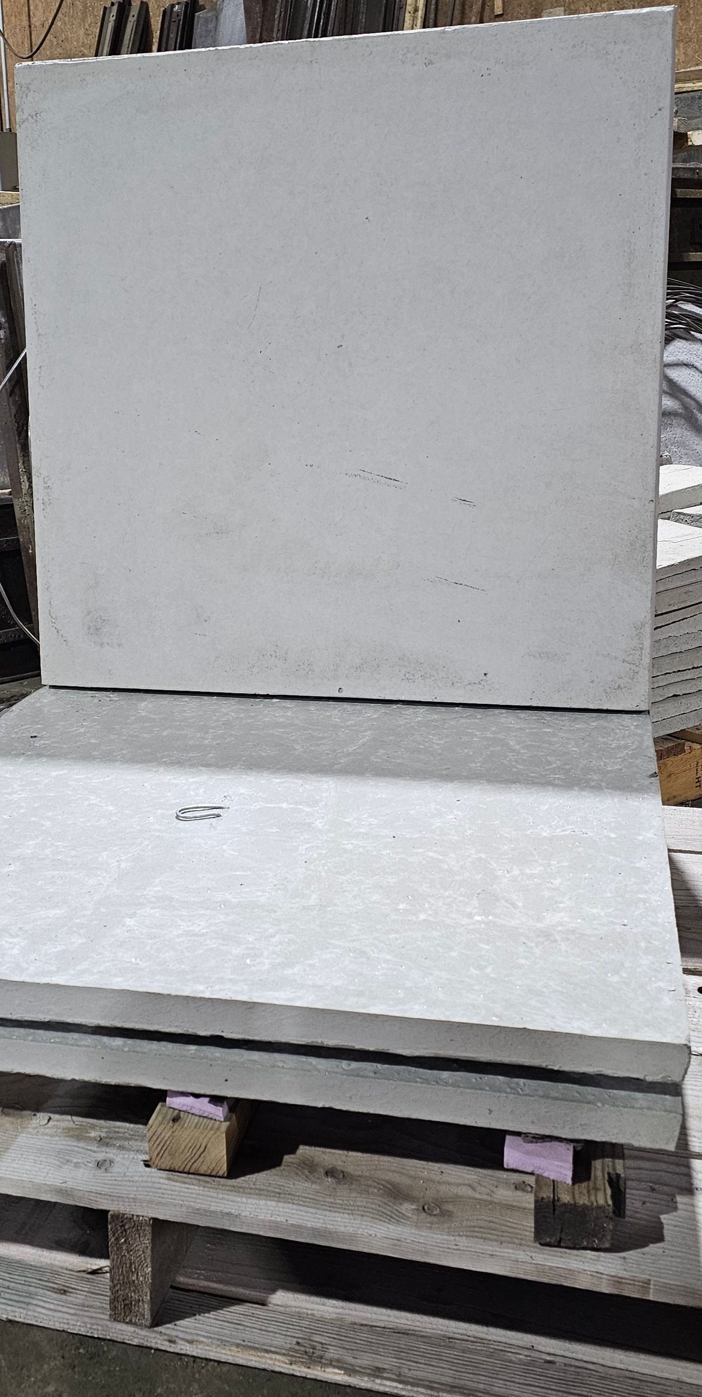 Two large gray stone slabs stacked on wooden pallets outdoors.