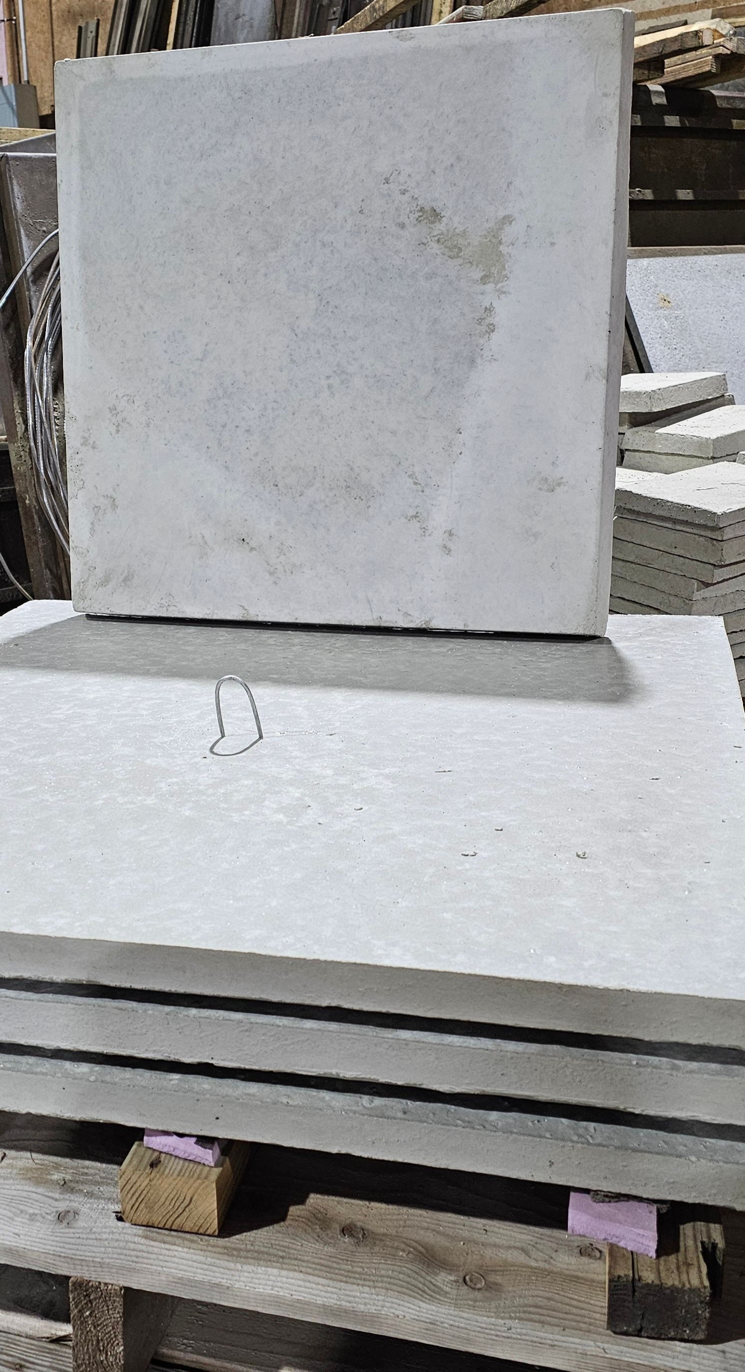 Stacked white stone slabs on a pallet outdoors, with one slab standing upright against the stack.