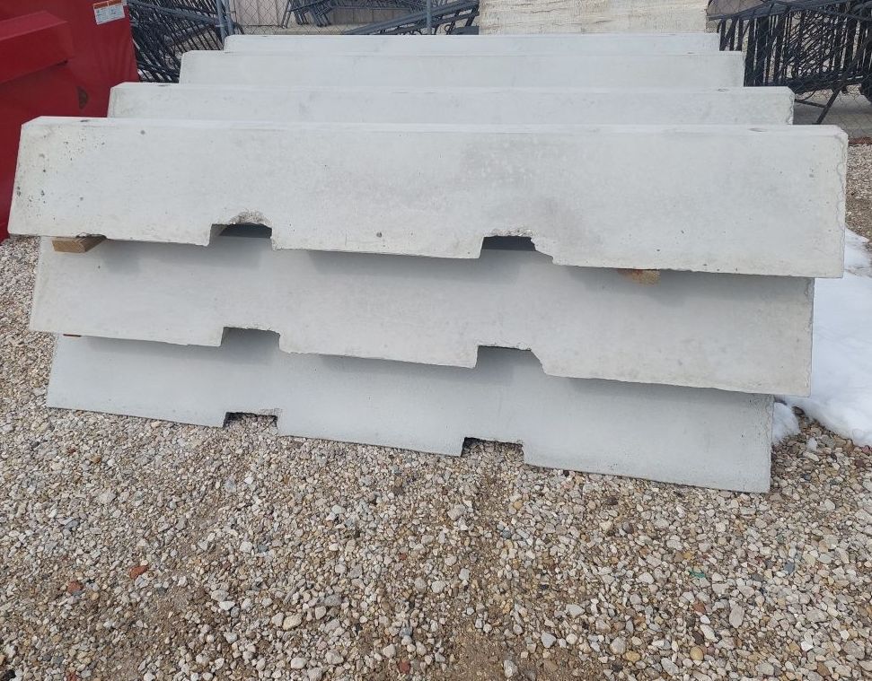 Stacked white concrete barriers on gravel outdoors