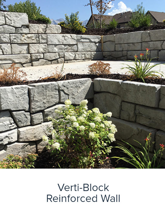 Tiered verti-block retaining wall with stone blocks and landscaping plants in a sunny yard
