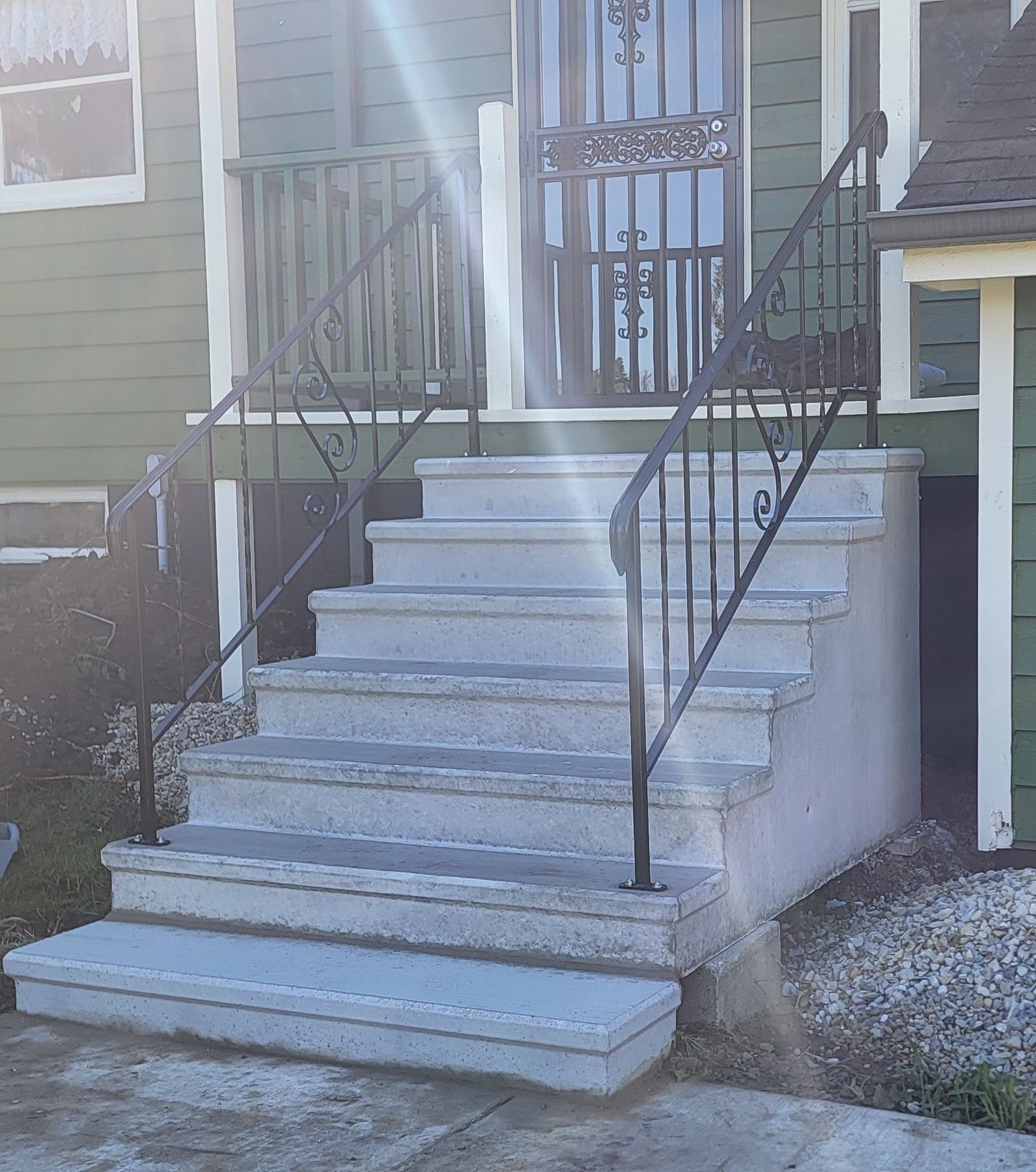 Front steps leading to a house entrance with black metal railings and white trim
