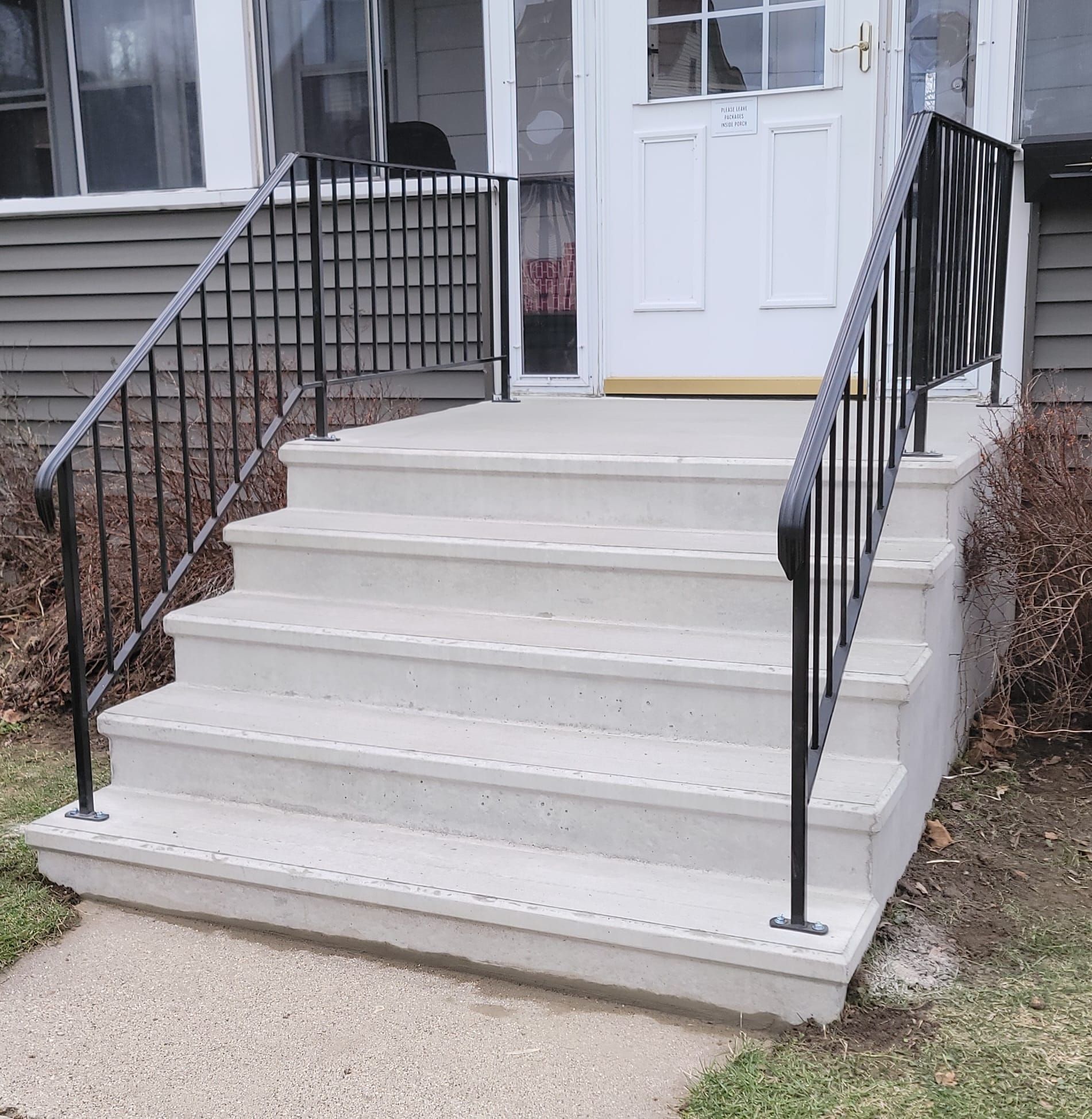 Front steps with black railings leading to a white front door of a house