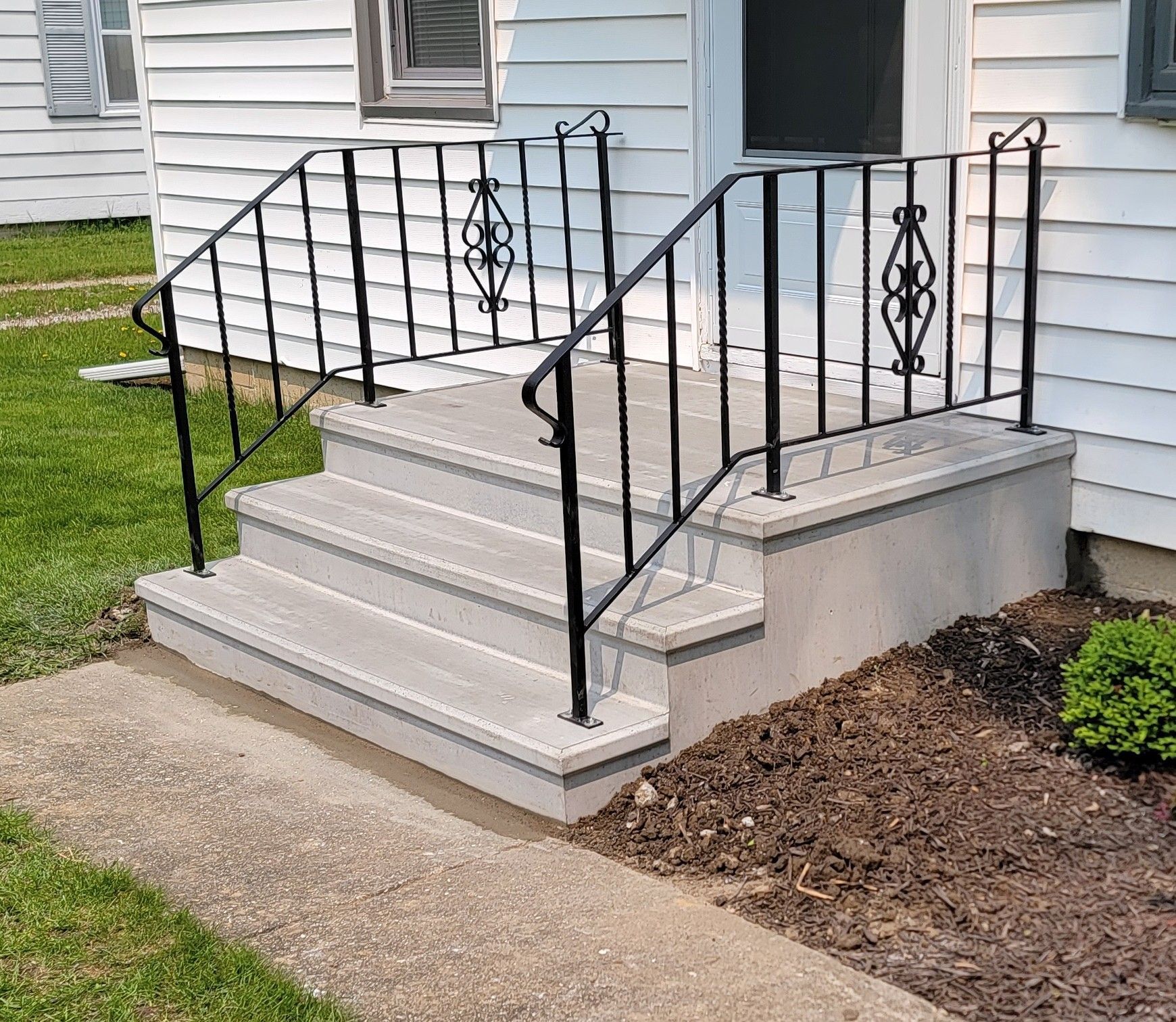 Front steps with black metal railings leading to a house entrance