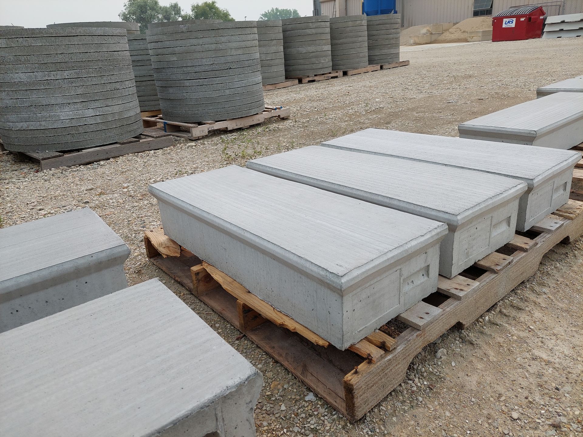 Stacked concrete blocks on pallets in an outdoor storage yard with gravel ground.