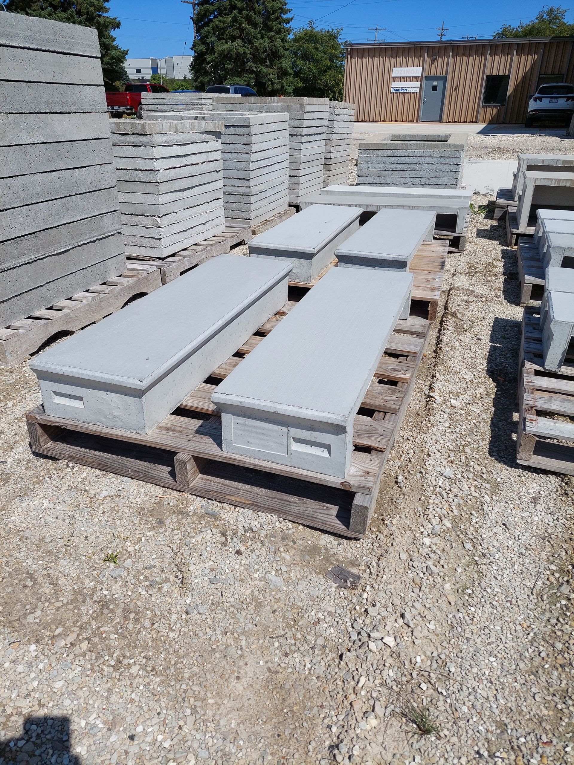 Concrete slabs stacked on pallets in an outdoor yard under bright sunlight