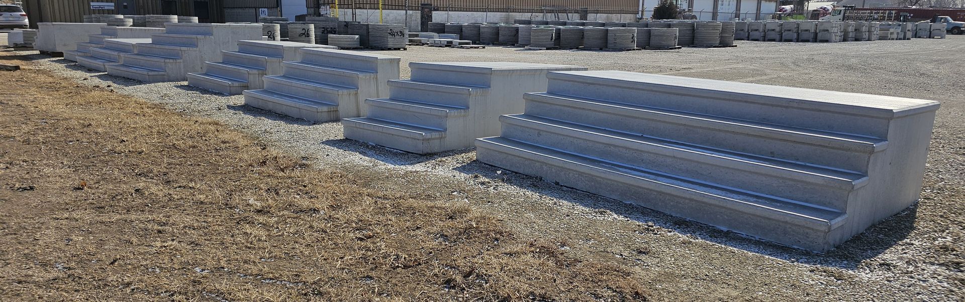 Rows of blue bleacher seats on a gravel field under bright sunlight