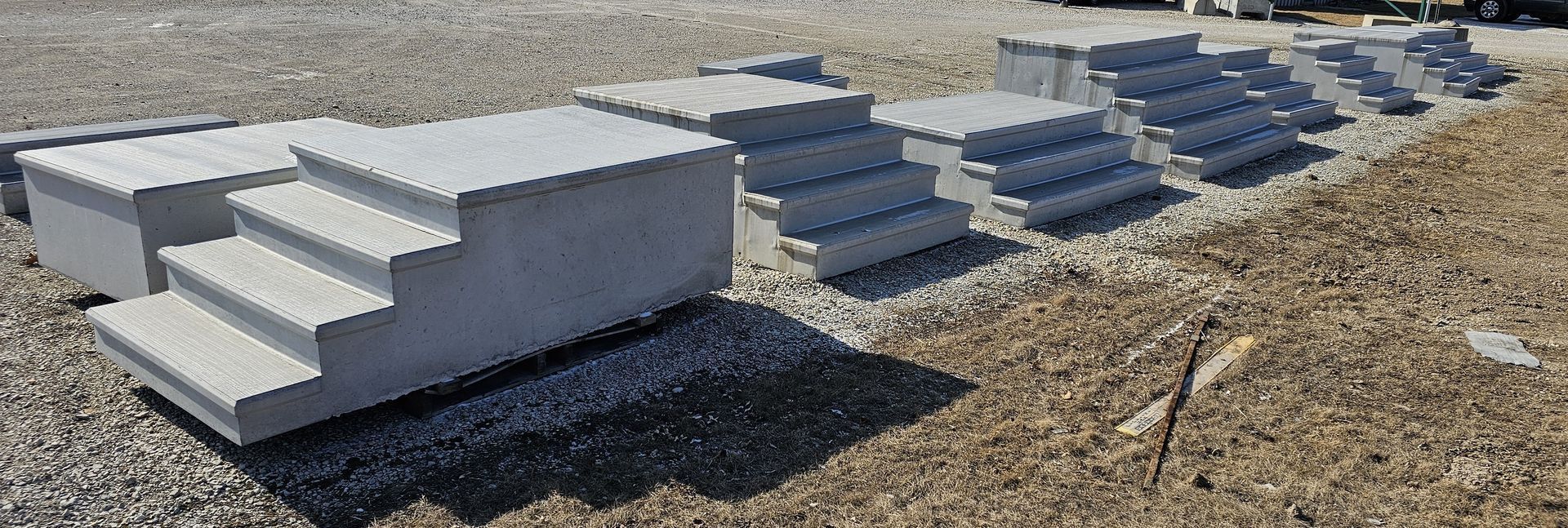Concrete steps and rows of pavers laid on gravel in an outdoor construction area