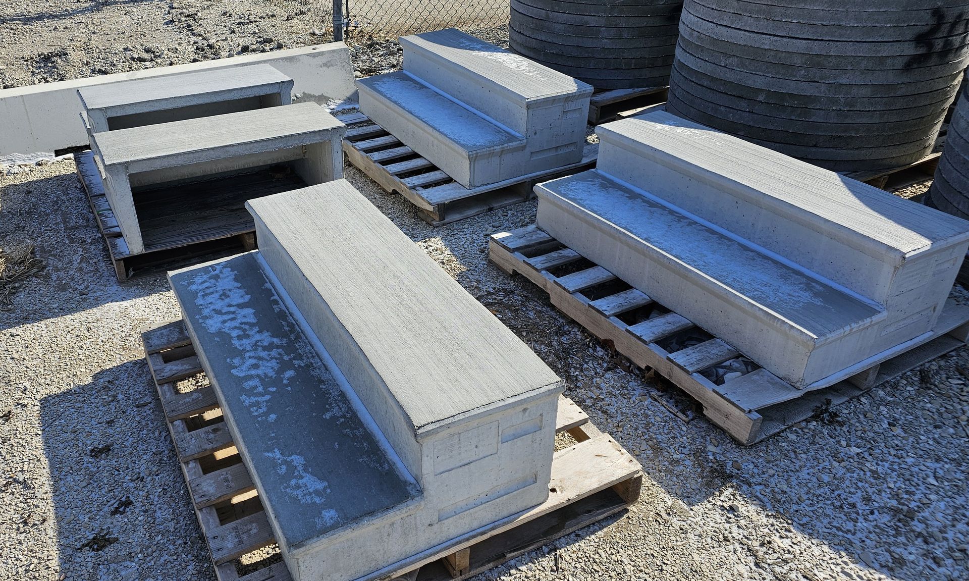 Stacked concrete blocks on wooden pallets in an outdoor gravel yard.