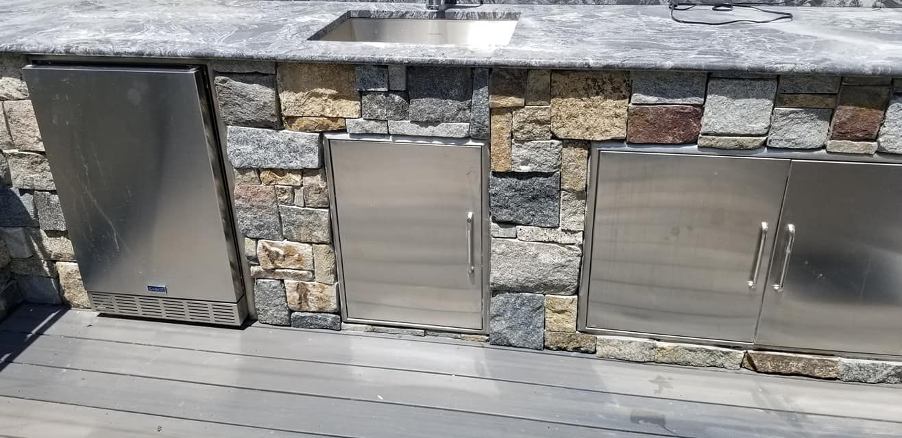 Outdoor kitchen with stainless steel doors and stone facade.