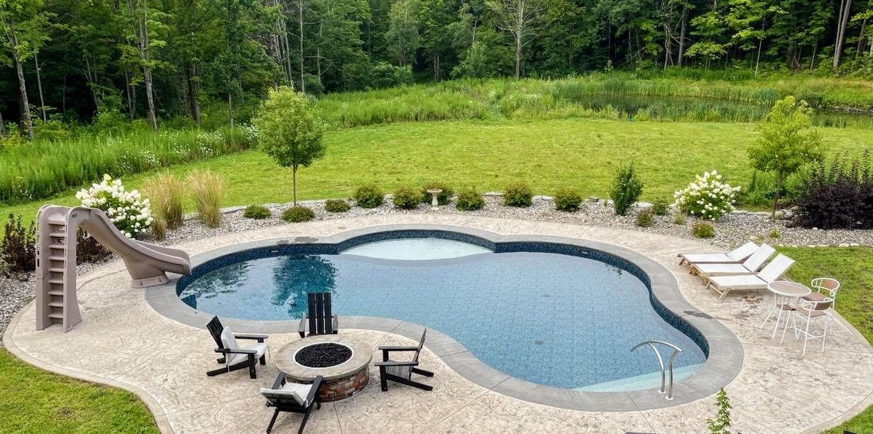 There is a large swimming pool with a fire pit in the middle of it.